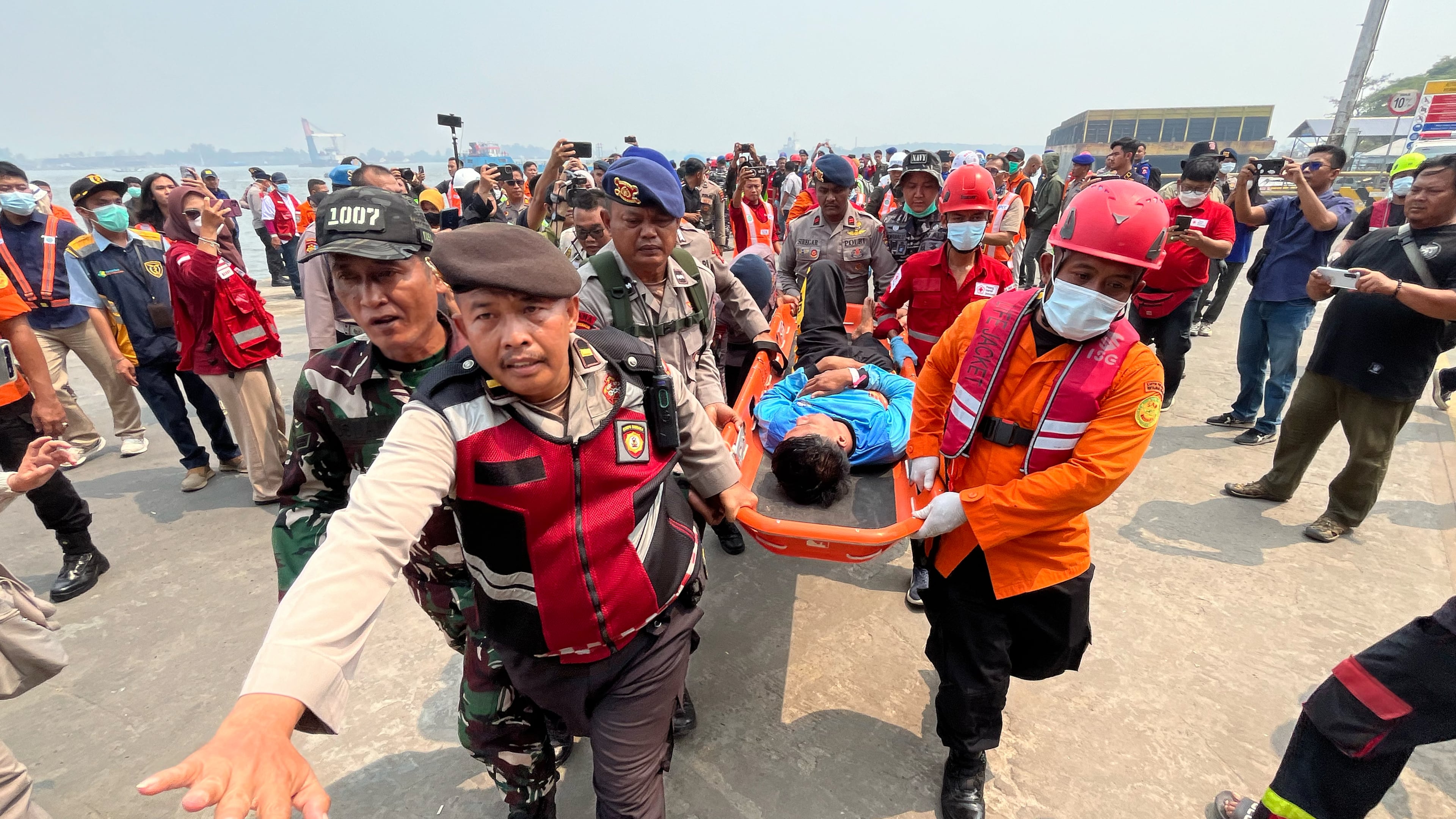 In this photo taken with a smartphone, rescuers carry a survivor from a passenger ferry overturned in bad weather in the Java Sea on a stretcher upon arrival at a port in Banjarmasin, South Kalimantan, Indonesia, Tuesday, Sept. 15, 2026. (AP Photo/Iman Satria)