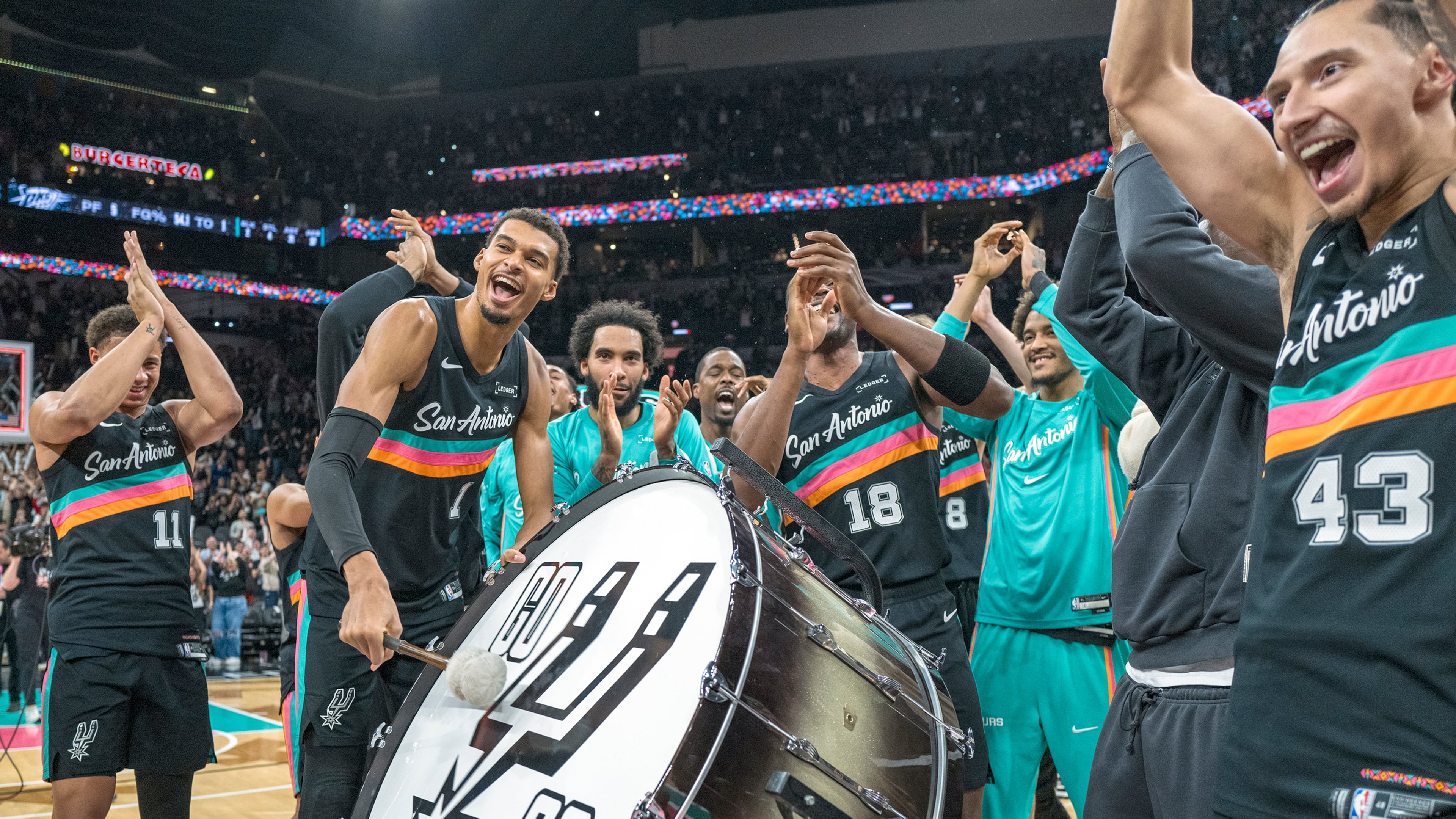 San Antonio Spurs forward Victor Wembanyama (1) hits on a drum as he and teammates celebrate with the Spurs fans after defeating the Oklahoma Thunder in an NBA basketball game in San Antonio, Tuesday, Dec. 23, 2025. (AP Photo/Rodolfo Gonzalez)