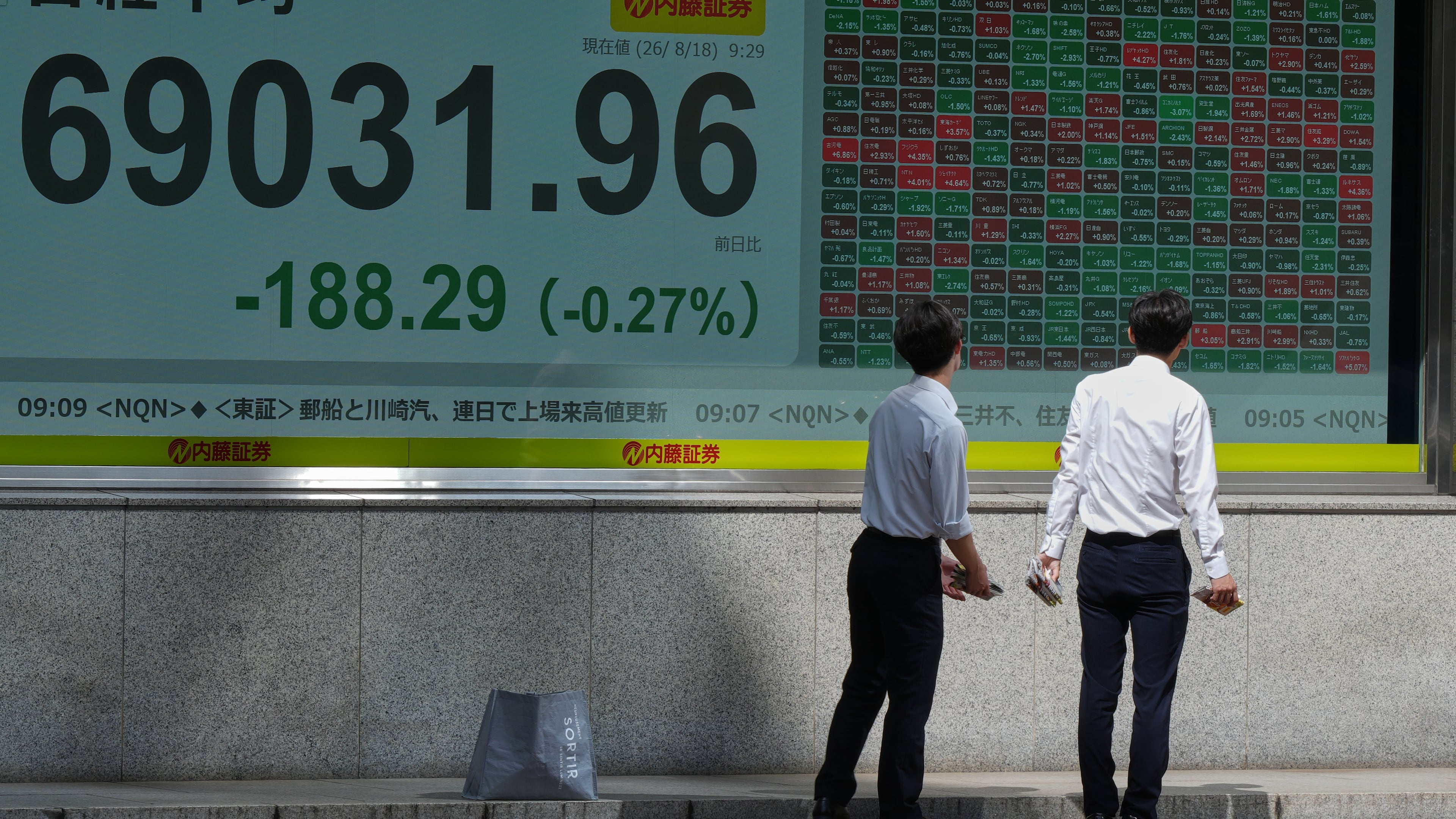 People look at an electronic stock chart board showing Japan's Nikkei index at a securities firm Tuesday, Aug. 18, 2026, in Tokyo. (AP Photo/Eugene Hoshiko)