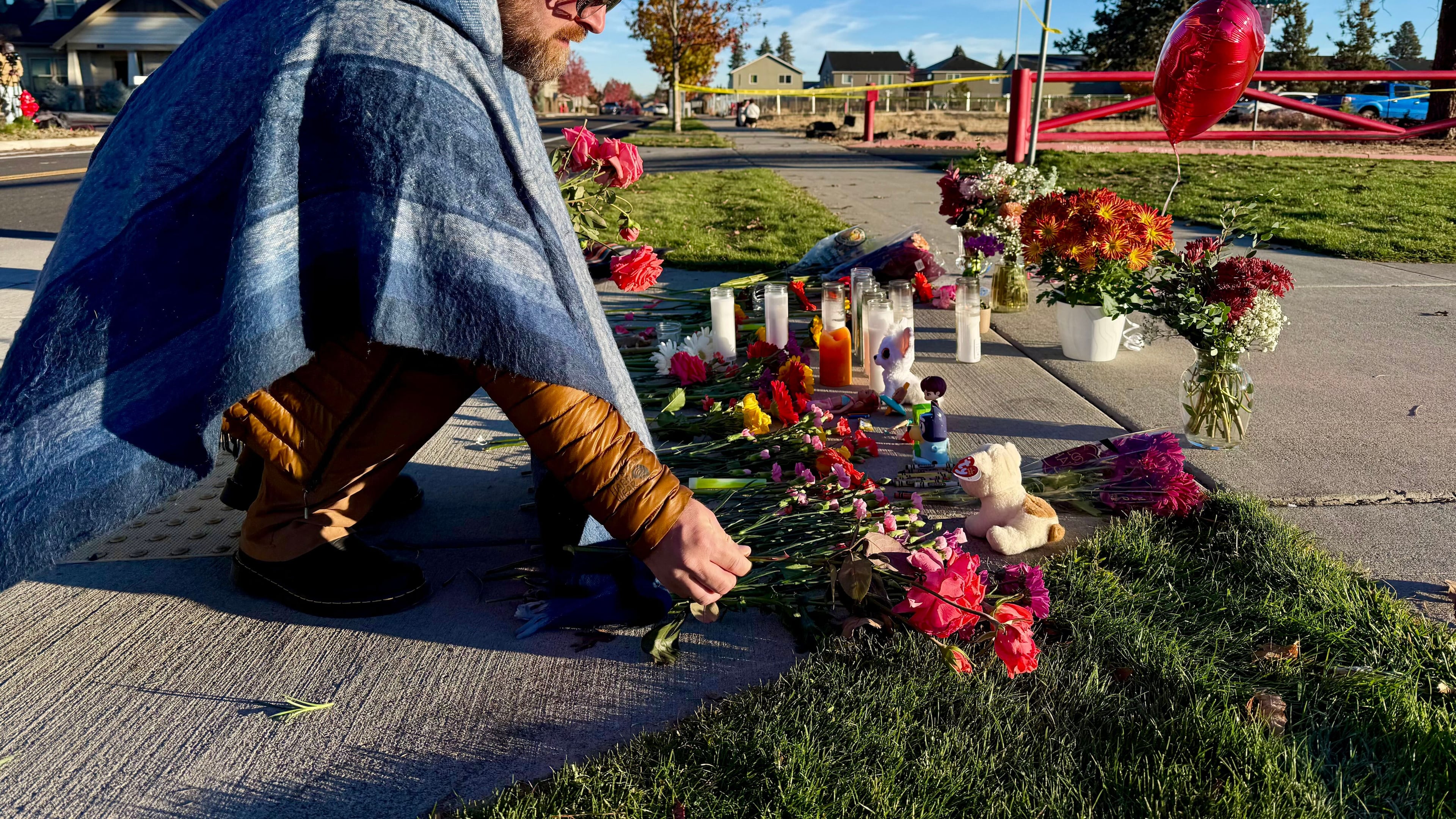 A person places flowers at a makeshift memorial on the other side of Silver Rail Elementary School in Bend, Ore., on Friday, Oct. 16, 2026, a day after a deadly shooting. (AP Photo/Haven Daley)