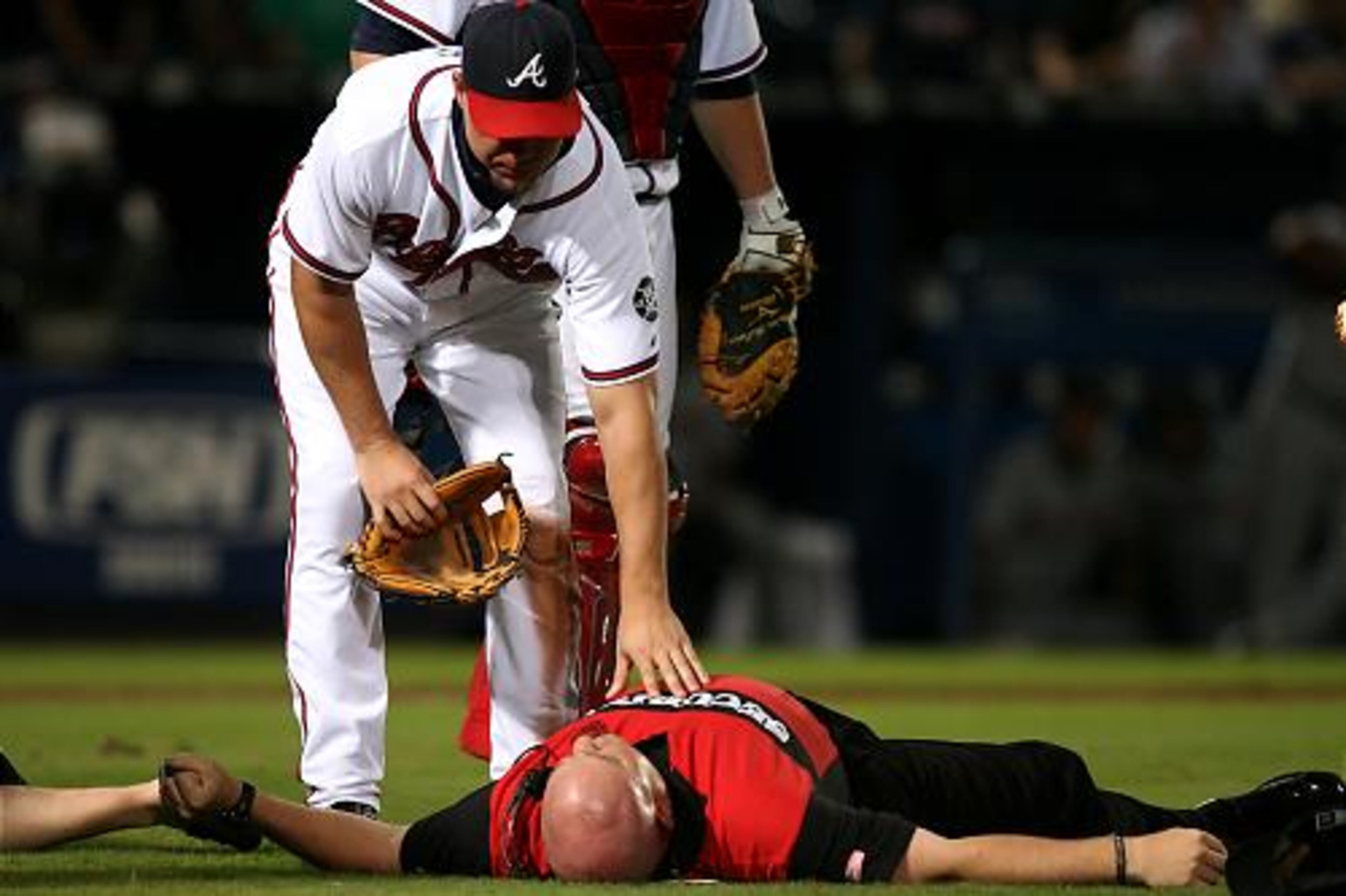 Chipper Jones checks on a security guard who was injured when he landed on his head attempting to stop fan who ran onto the field in the ninth inning. The game was delayed about 10 minutes as medical personnel tended to the guard. He eventually got up, walked to a cart and was taken off the field.