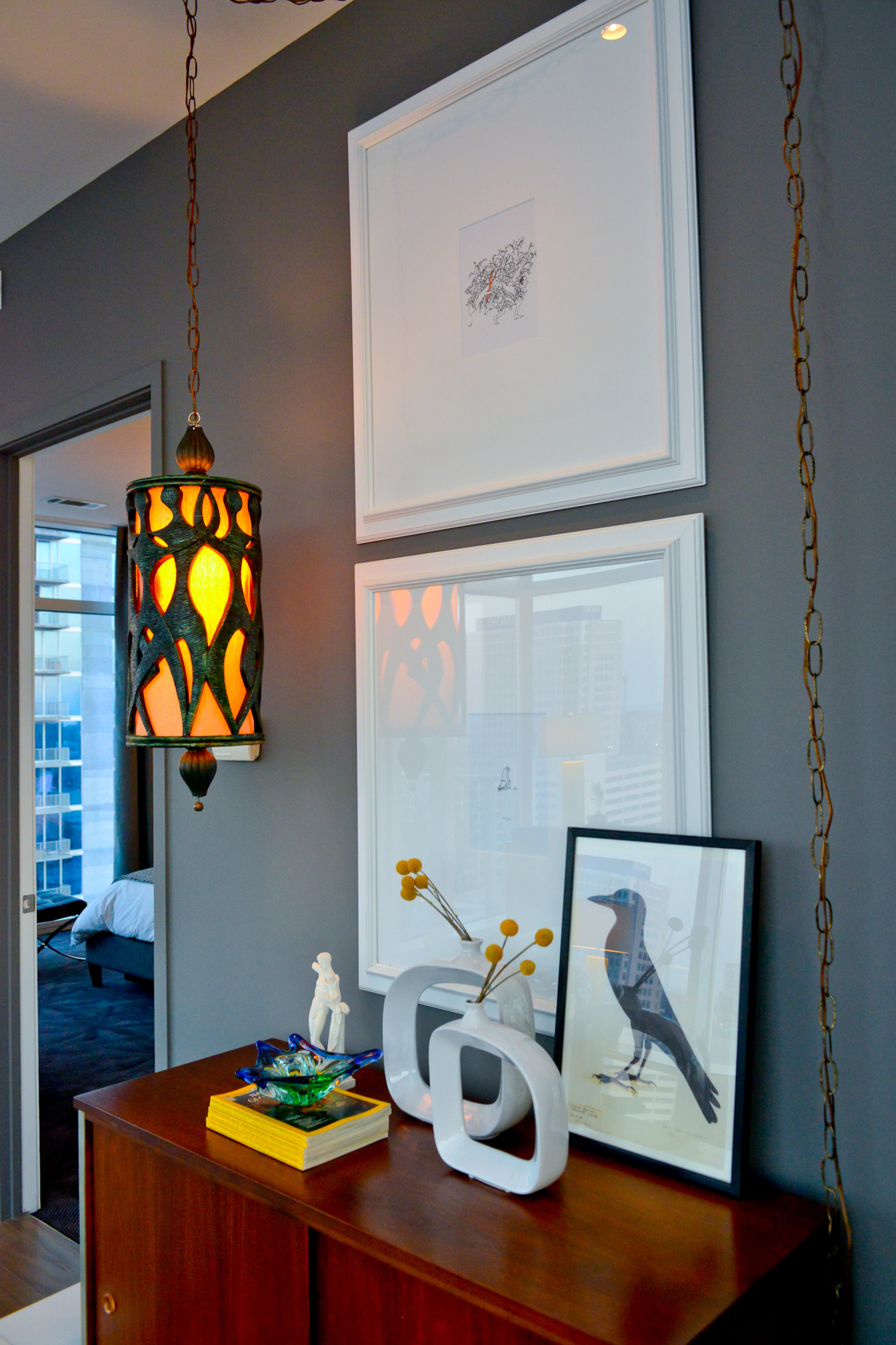 A pendant from Decades Antiques and Vintage adds a glow to framed pages from Shel Silverstein's book, "The Giving Tree," in Marc Castillo's condo. Castillo wanted the condo to be retro without being kitschy, and working with designer Steve McClure, he purchased items such as a vintage buffet table with stainless accents, also from Decades Antiques and Vintage.(Christopher Oquendo Photography)