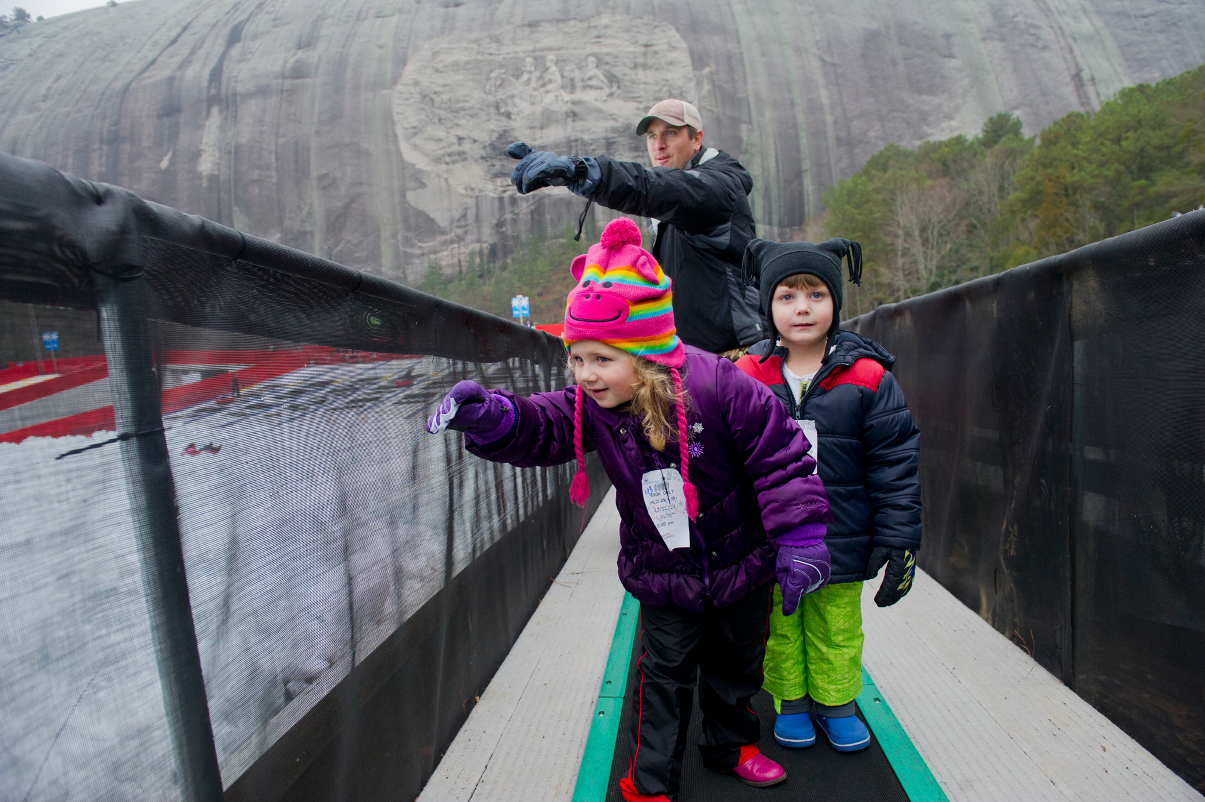 December 21, 2014 Stone Mountain - Emilie Hart (center), her cousin Hunter Futrell (right) and Hunter's father John bring their tubes to the top of the hill during Snow Mountain at Stone Mountain Park on Sunday, December 21, 2014. This is the seventh season that the main lawn at the park has been transformed into a winter wonderland. JONATHAN PHILLIPS / SPECIAL