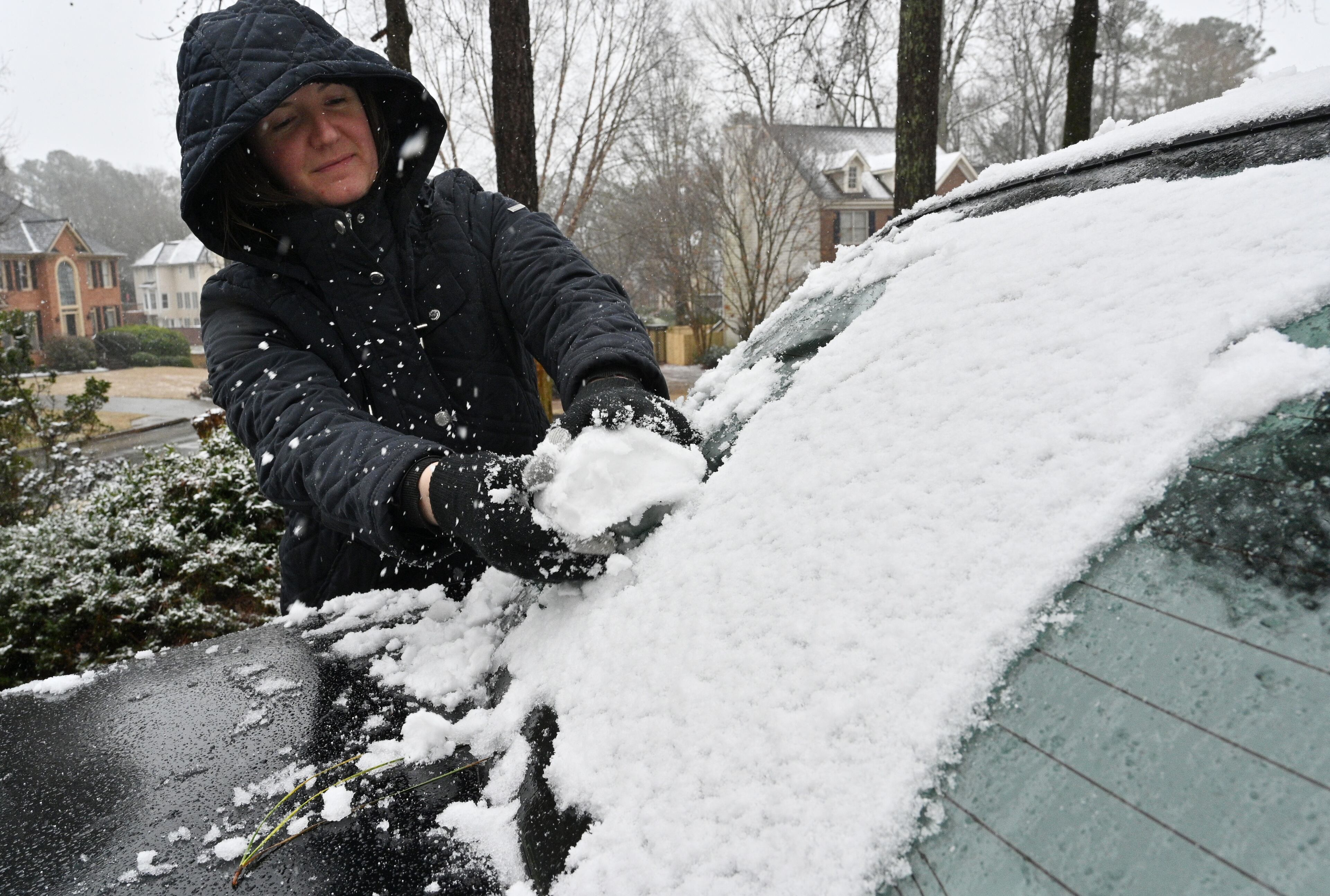 January 16, 2022 Lawrenceville - Jessica Richie gathers snow as she helps her children building a snowman at their front yard in Lawrenceville on Sunday, January 16, 2022. Snowfall continues to move south of I-285 and south Fulton and Coweta counties could see up to 2 inches of snow by Sunday evening. Major impacts near Lake Lanier and into the North Georgia mountains are being felt and certain spots could see up to 10 inches of snow. As of around noon, snow is moving through Troup and Coweta counties, as Fayette and Clayton counties still patiently wait for some flurries amidst the rain and some wintry mix. (Hyosub Shin / Hyosub.Shin@ajc.com)