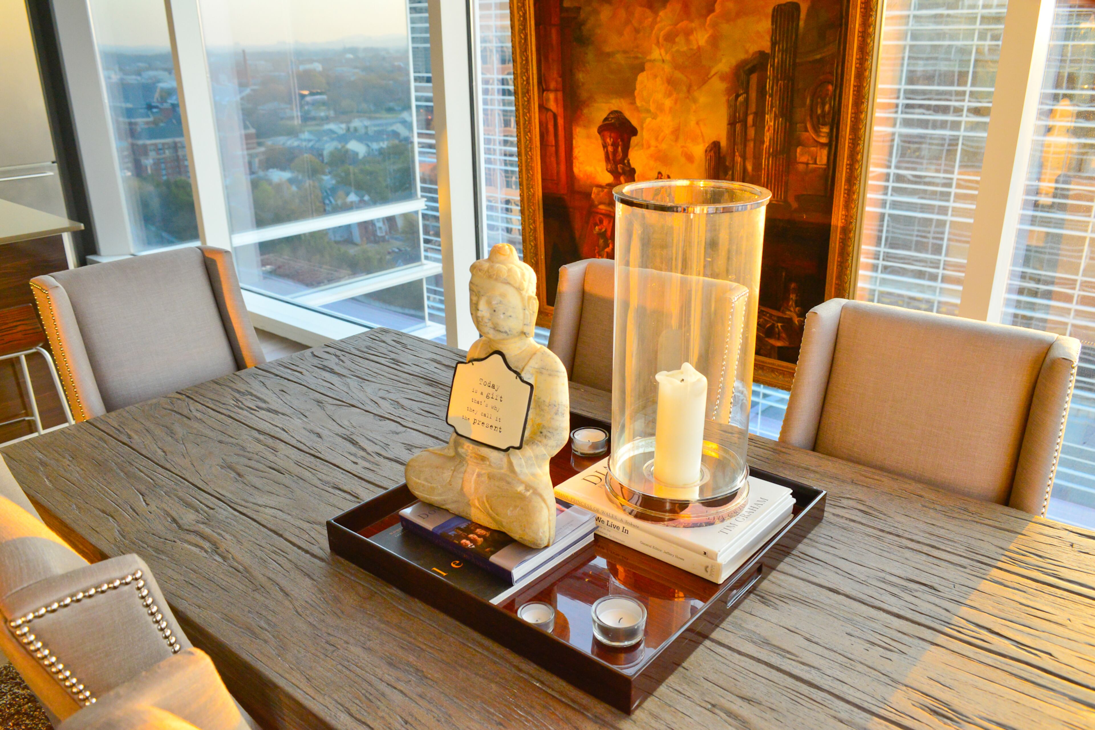 Twilight is Marc Castillo's favorite times of day in his downtown Atlanta condo, and dining chairs with nail head trim were custom made for the Bernhardt table. A Vernet painting believed to be more than 200 years old creates ambiance in the dining room, with the skyline backdrop. (Christopher Oquendo Photography)