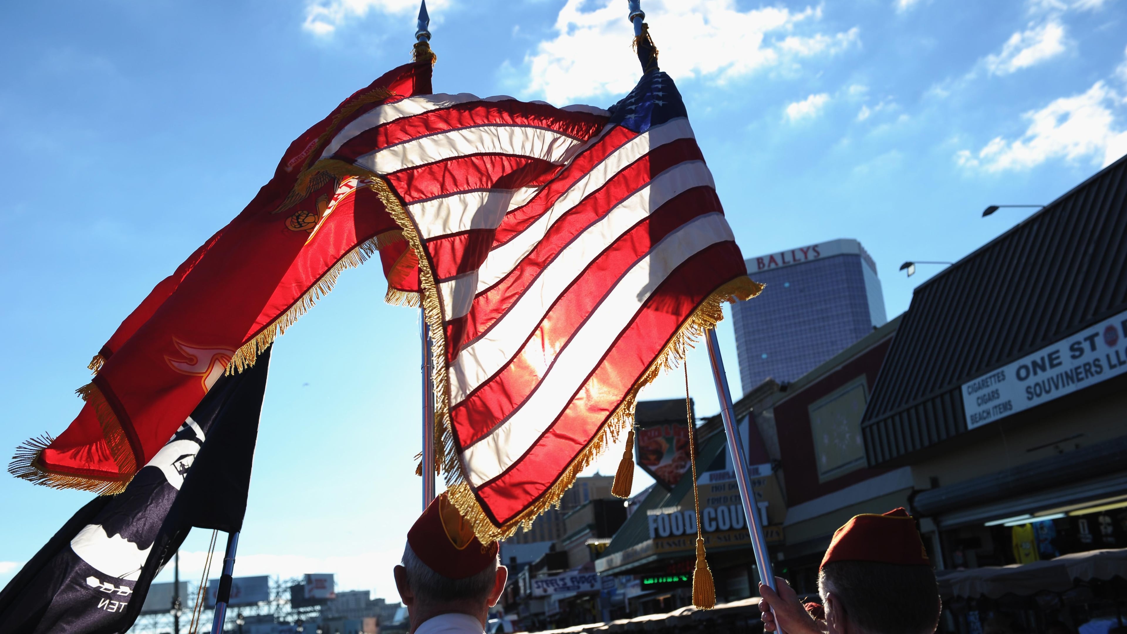 A photo of veterans holding American and miltary flags in a parade. A Florida business was cited by the City of Jacksonville for flying military flags atop its building because it violates a city ordinance.