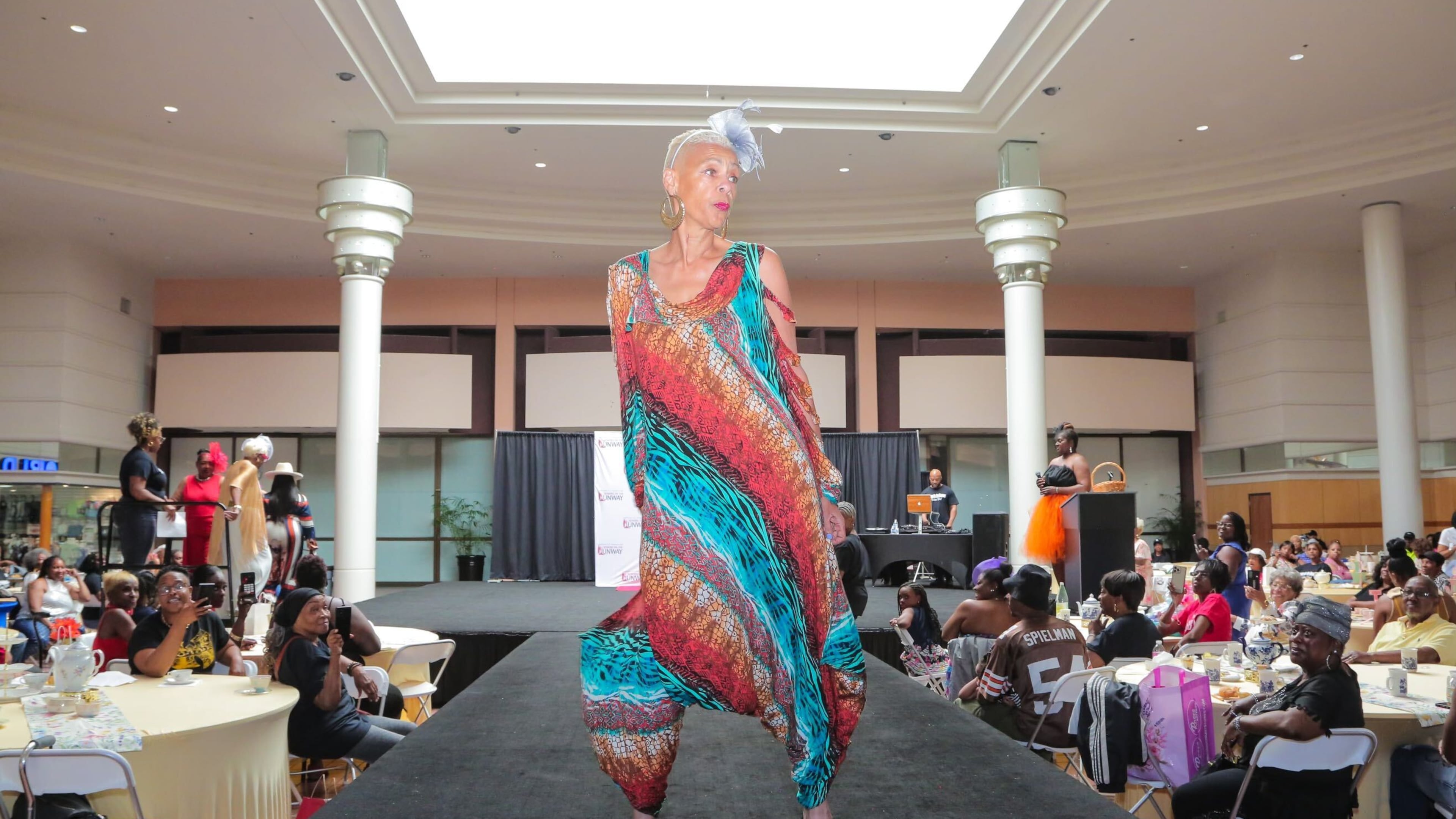 A model wearing a colorful dress struts on the catwalk at the 'Seniors on the Runway' event on May 4, 2024, at Greenbriar Mall in Atlanta.