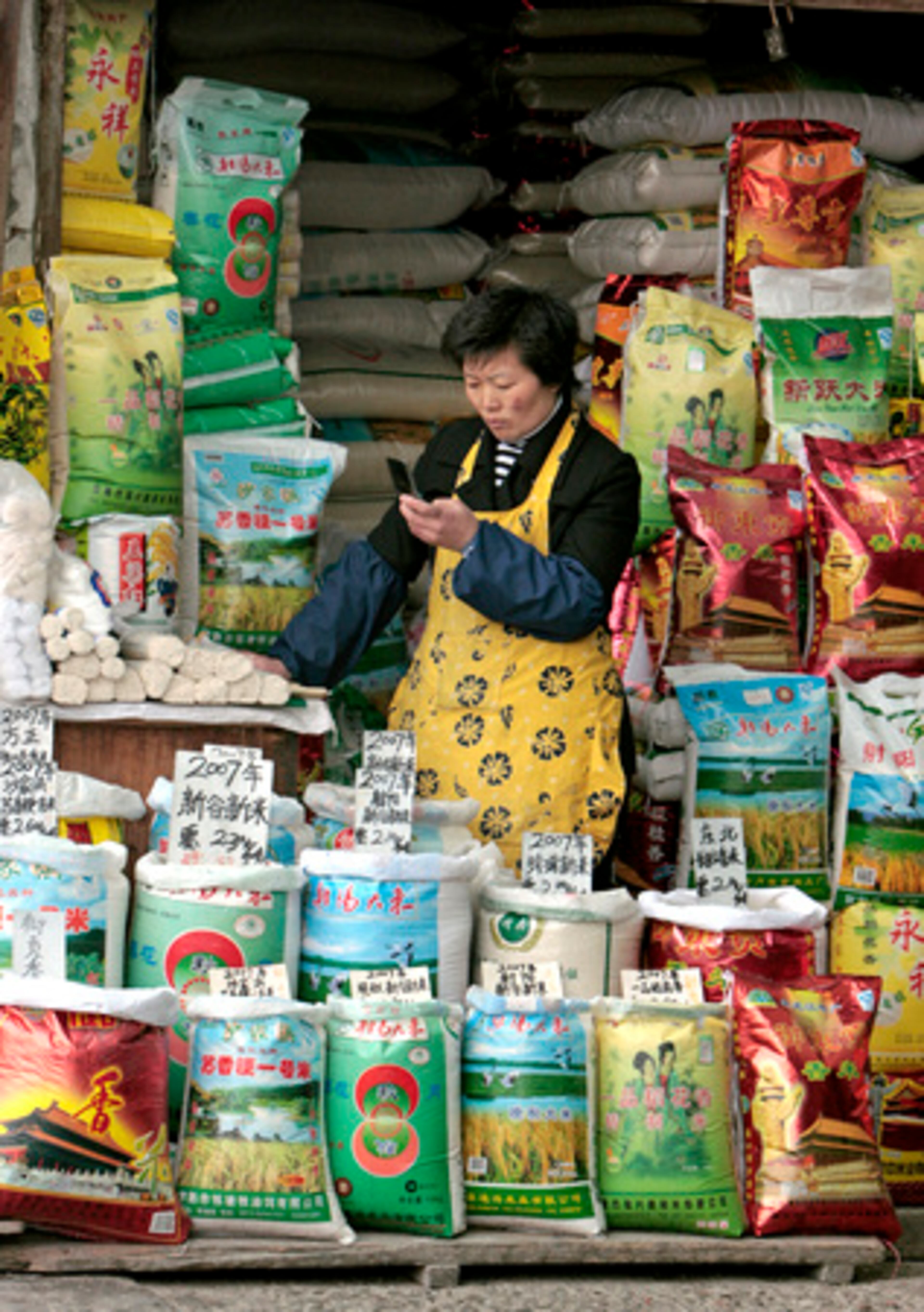 A rice vendor uses her mobile phone at a wholesale market in Shanghai.