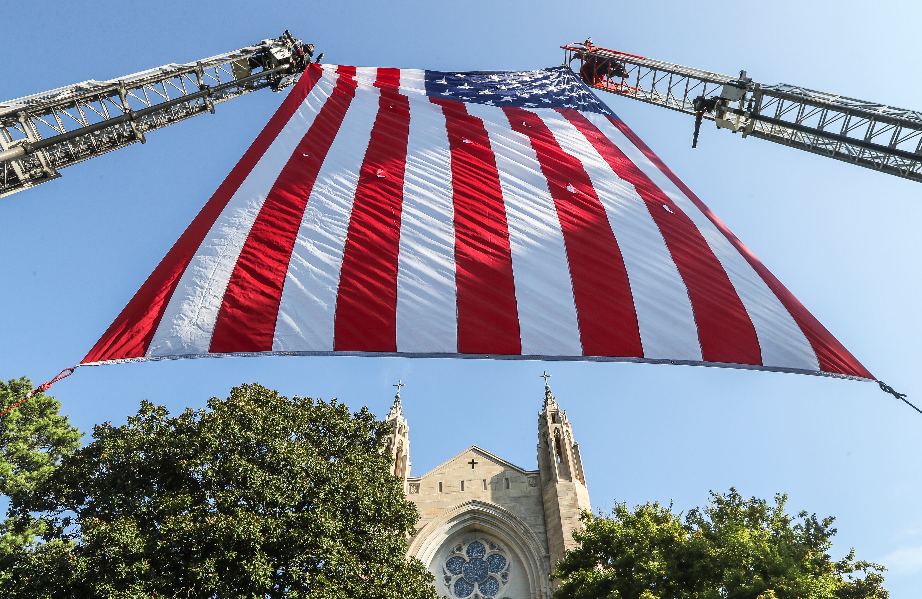 September 11, 2023 Atlanta: Atlanta firefighters post a giant American flag between ladders at the Cathedral of Christ the King. Atlanta police and firefighters were in attendance on Monday, September 11, 2023 at the Cathedral of Christ the King, 2699 Peachtree Road, NE in Buckhead in observance of the Blue Mass. The annual Mass honors public safety officials and first responders. City of Atlanta Mayor, Andre Dickens, along with police, fire officials and honor guards participated in the solemn Mass led by Rector, Monsignor Francis G. McNamee. Wreaths were posted in front of the of the church, honoring those who lost their lives on Sept. 11, 2001. The Blue Mass tradition began in 1934, when a priest from the Archdiocese of Baltimore, Father Thomas Dade formed the Catholic Police and Firemen’s Society. (John Spink / John.Spink@ajc.com)