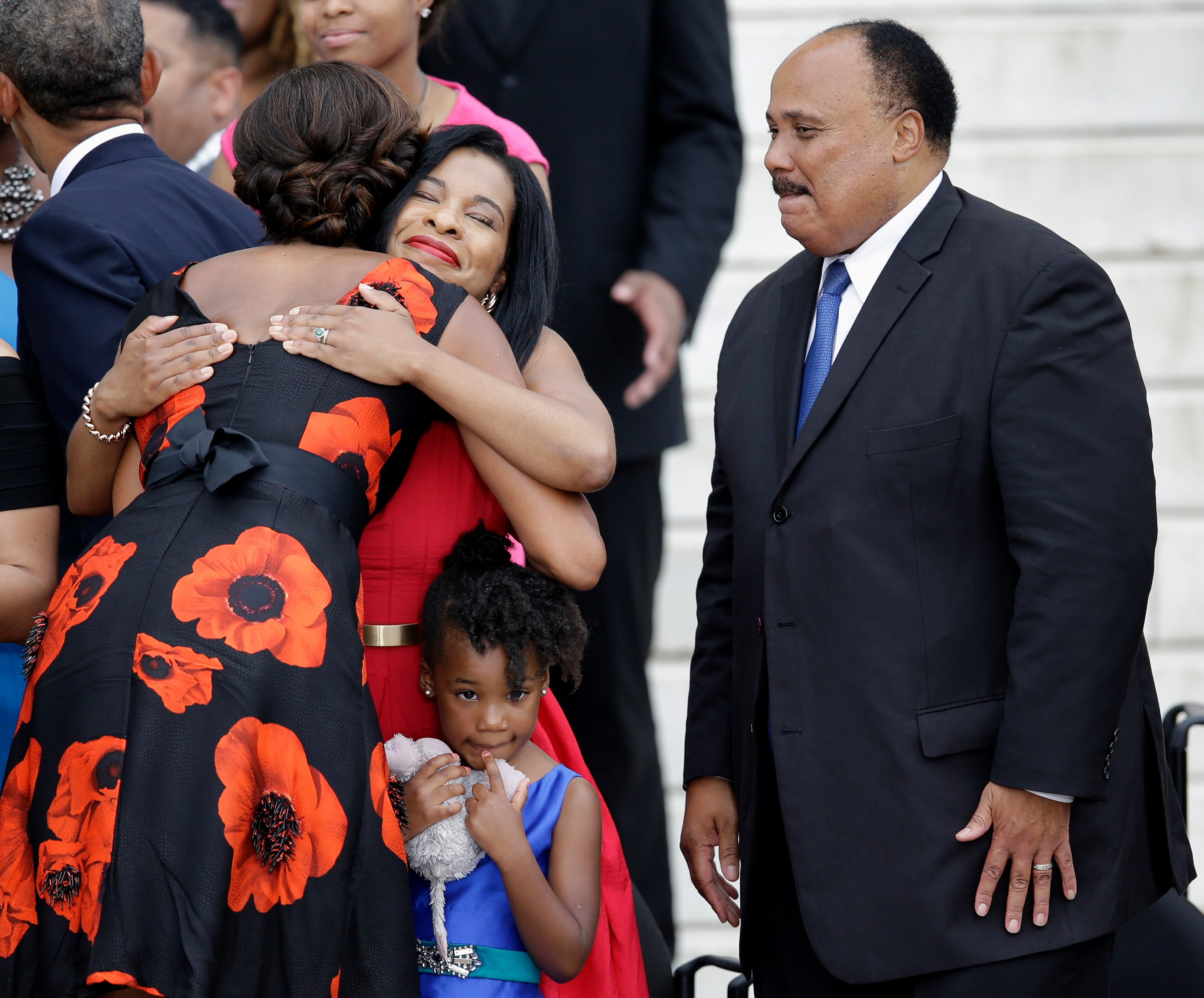 First lady Michelle Obama hugs Arndrea Waters, wife of Martin Luther King III, son of Martin Luther King Jr., as their daughter Yolanda Renee King looks to the crowd at the Let Freedom Ring ceremony at the Lincoln Memorial in Washington, Wednesday, Aug. 28, 2013, to commemorate the 50th anniversary of the 1963 March on Washington for Jobs and Freedom. It was 50 years ago today when Martin Luther King Jr. delivered his "I Have a Dream" speech from the steps of the memorial. (AP Photo/Carolyn Kaster)