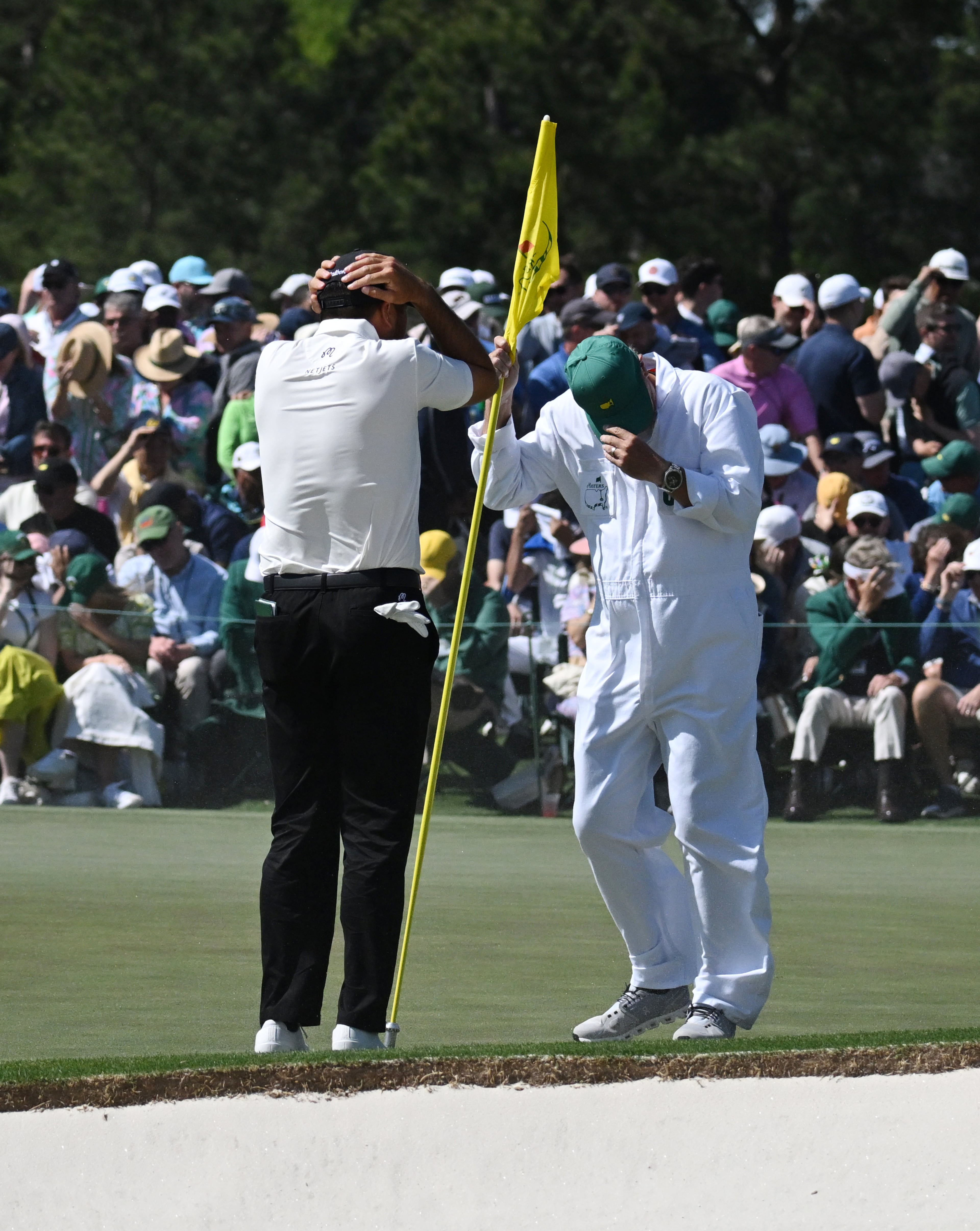 Jason Day and caddie Luke Reardon shield themselves from wind and sand on 18th green during second round of the 2024 Masters Tournament at Augusta National Golf Club, Friday, April 12, 2024, in Augusta, Ga. (Hyosub Shin / Hyosub.Shin@ajc.com)