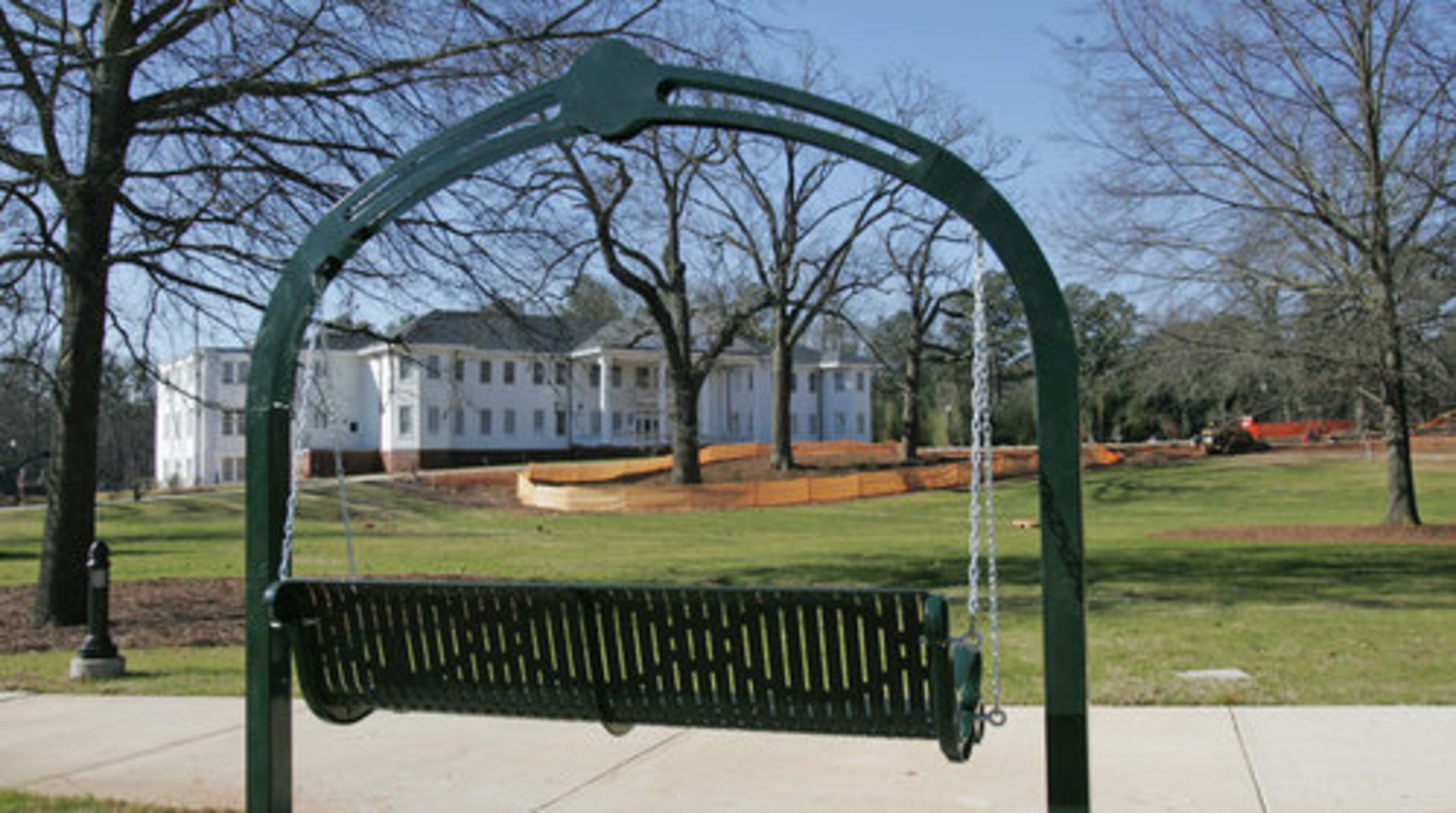 Beyond a swinging bench in Taylor-Brawner Park is the historic Brawner Hospital building.