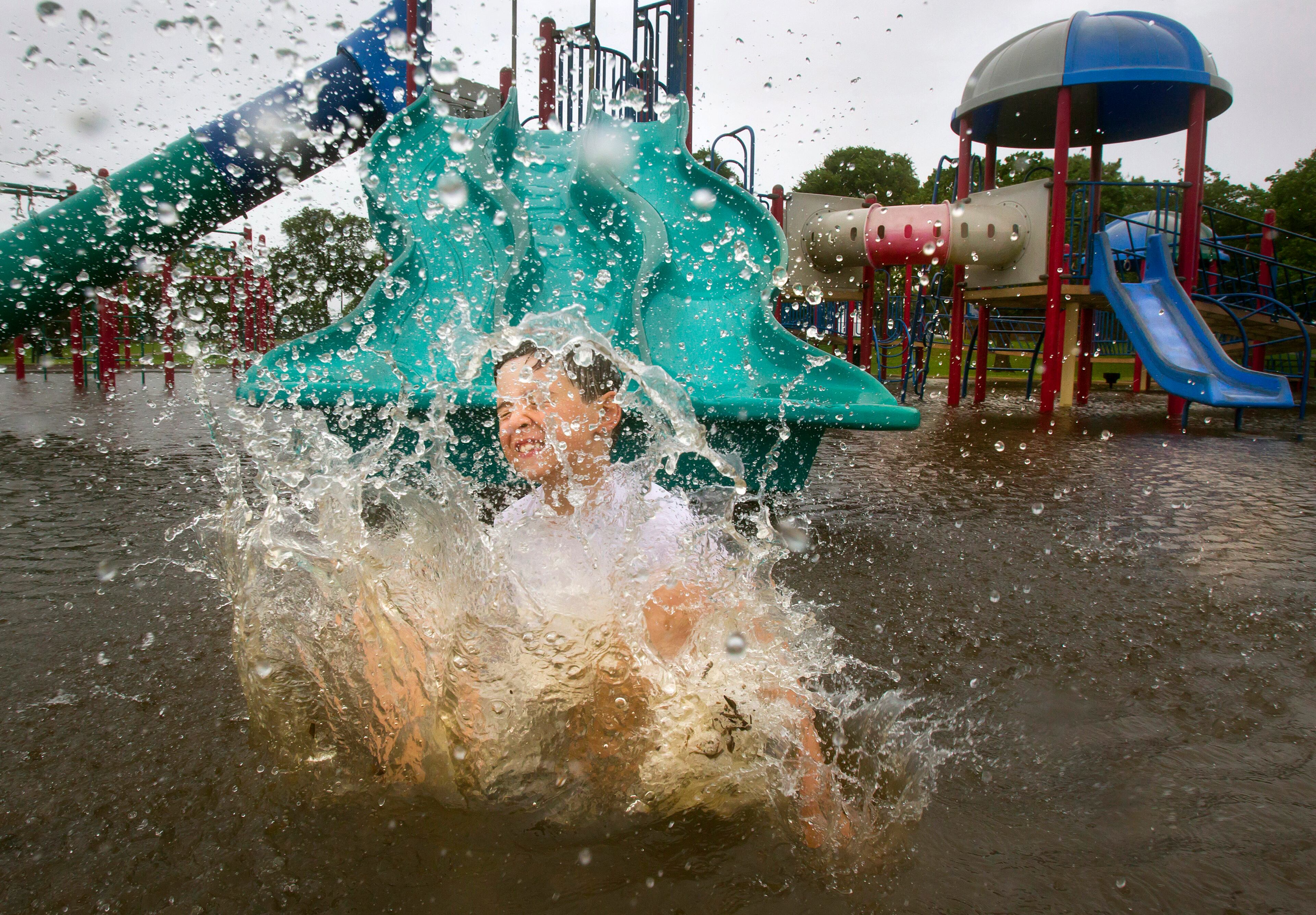 Seven-year-old Devin Vincent splashes down from a slide on a flooded playground at Clear Lake Park in southern Harris County, Texas, Tuesday, June 16, 2015. Area creeks and bayous were flooded by rains and the tidal surge from Tropical Storm Bill. Tropical Storm Bill moved slowly over inland Texas on Tuesday, bringing another round of heavy rains to a state weary from recent deadly floods, evacuations and washed-out roads. (Stuart Villanueva/The Galveston County Daily News via AP)