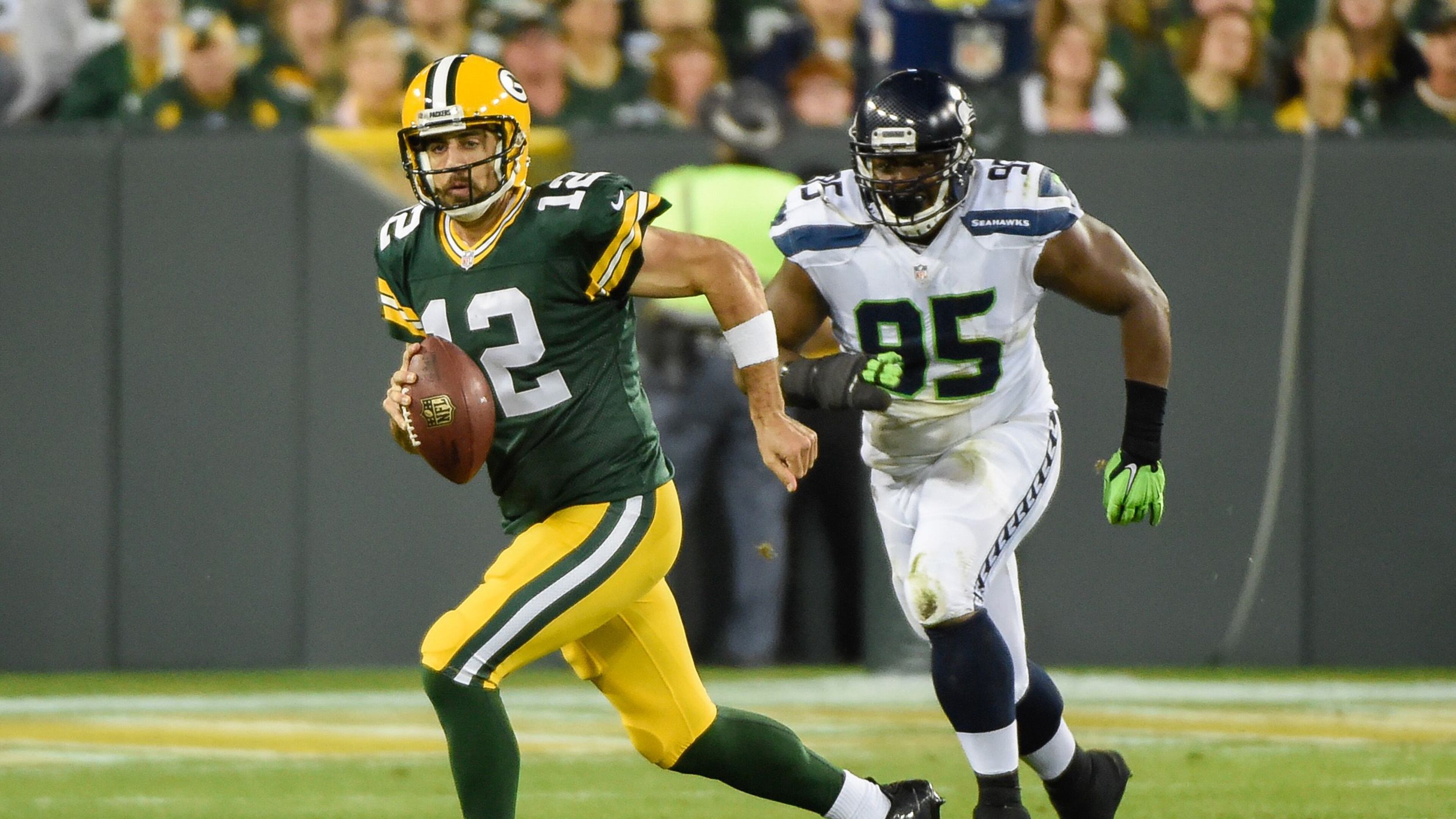 Green Bay Packers quarterback Aaron Rodgers (12) scrambles away from Seattle Seahawks defensive end Demarcus Dobbs (95) in the second quarter at Lambeau Field.