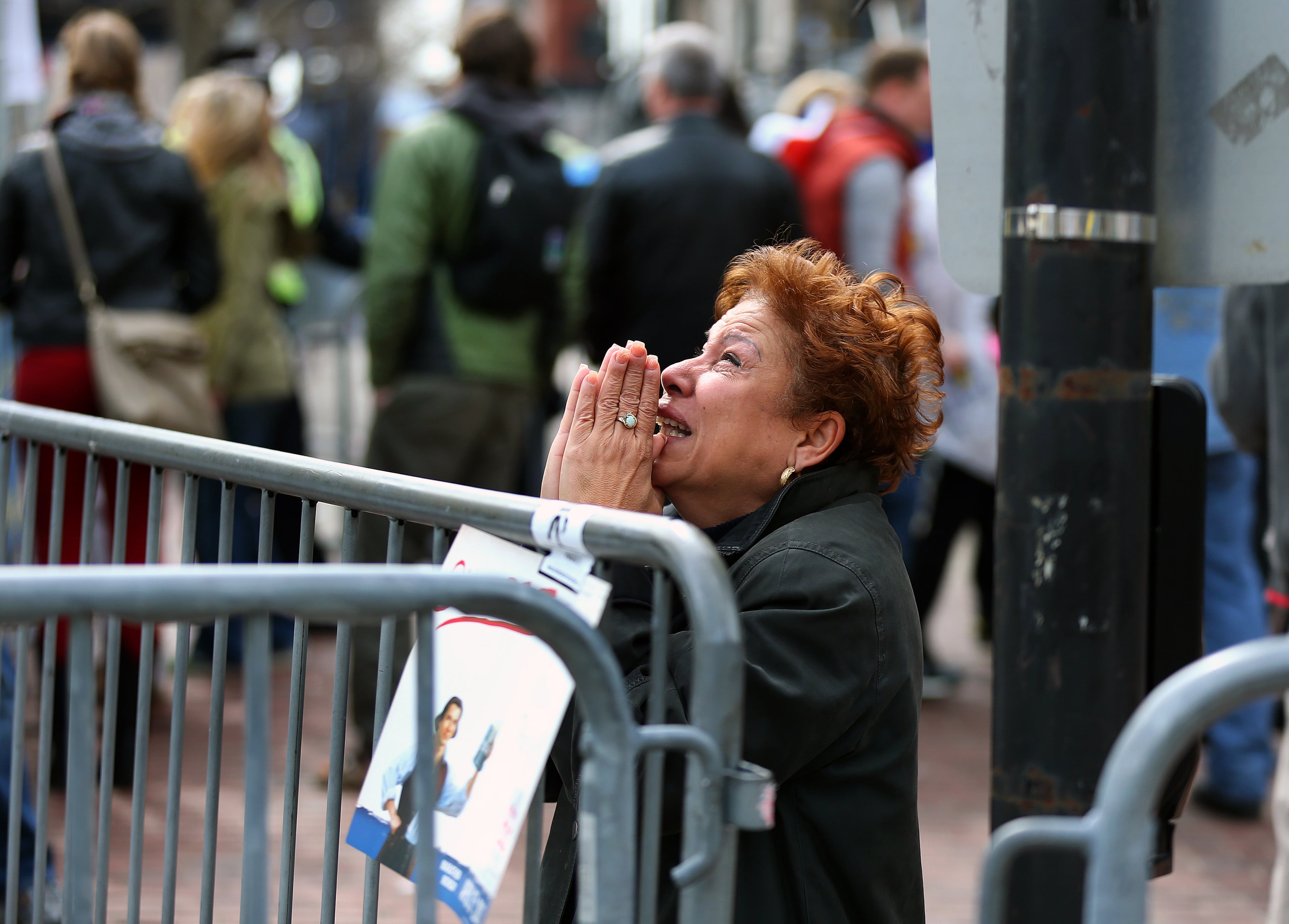 A distraught woman kneels and prays near the finish line.