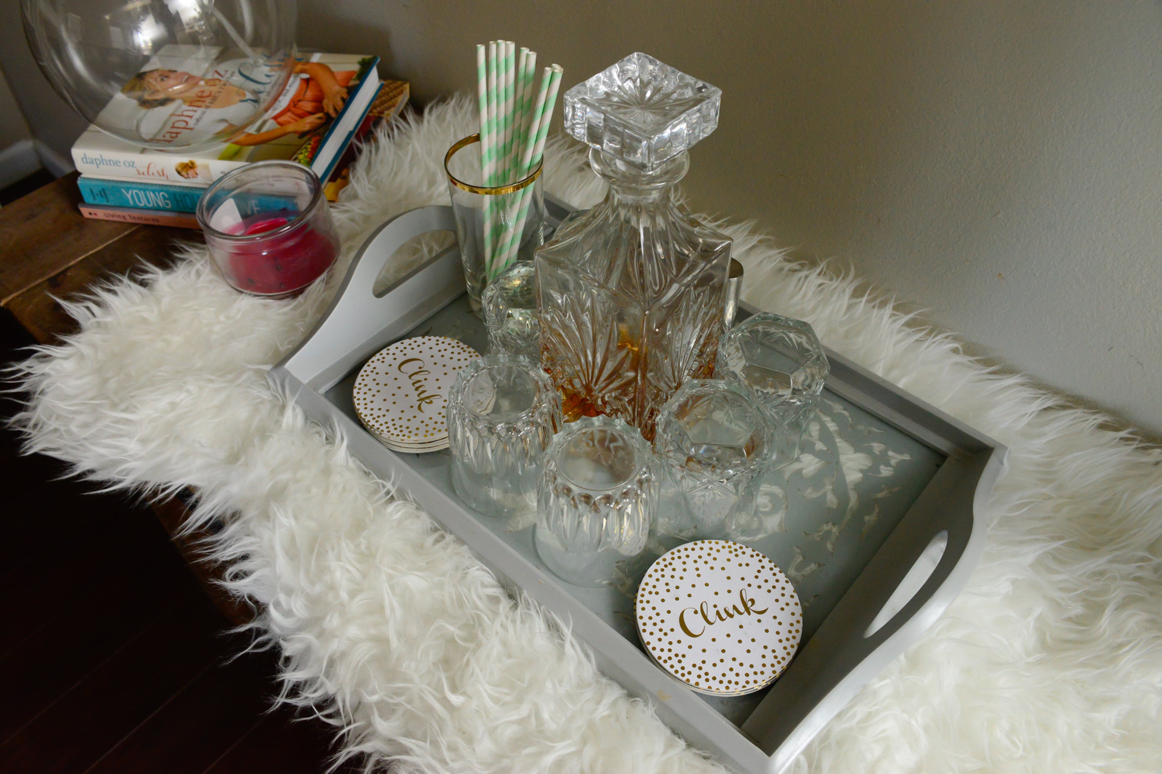 For a makeshift bar area, Erin Marshall gathered a bar decanter from Macy's that was a gift and cups from Dollar Tree, on a tray from Target. A fur rug from Ikea is unexpected and adds more interest to the table in the family room.