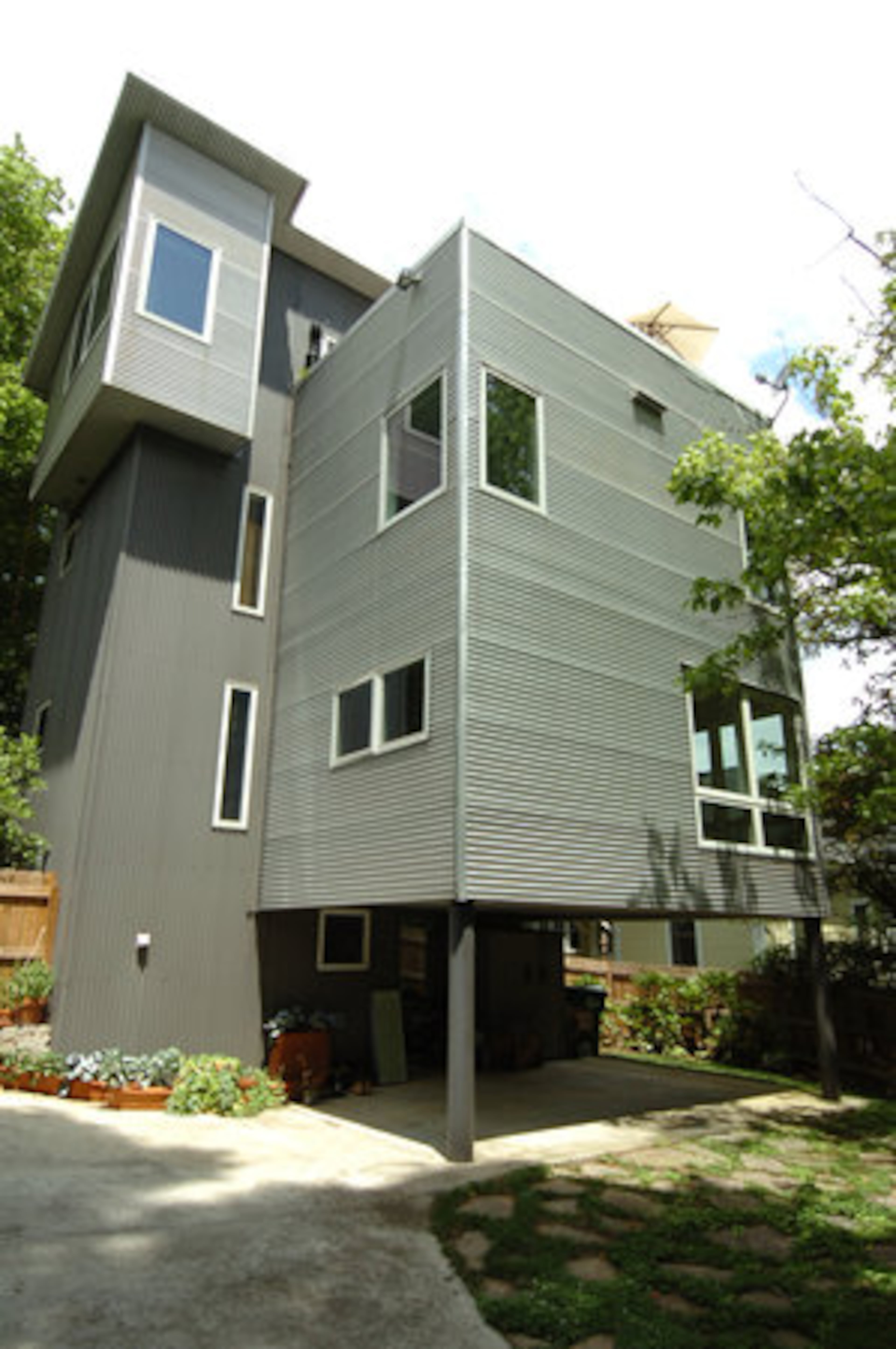 The multi-level Inman Park 'treehouse,' covered completely in galvanized aluminum, sits in the crook of a neighborhood road.