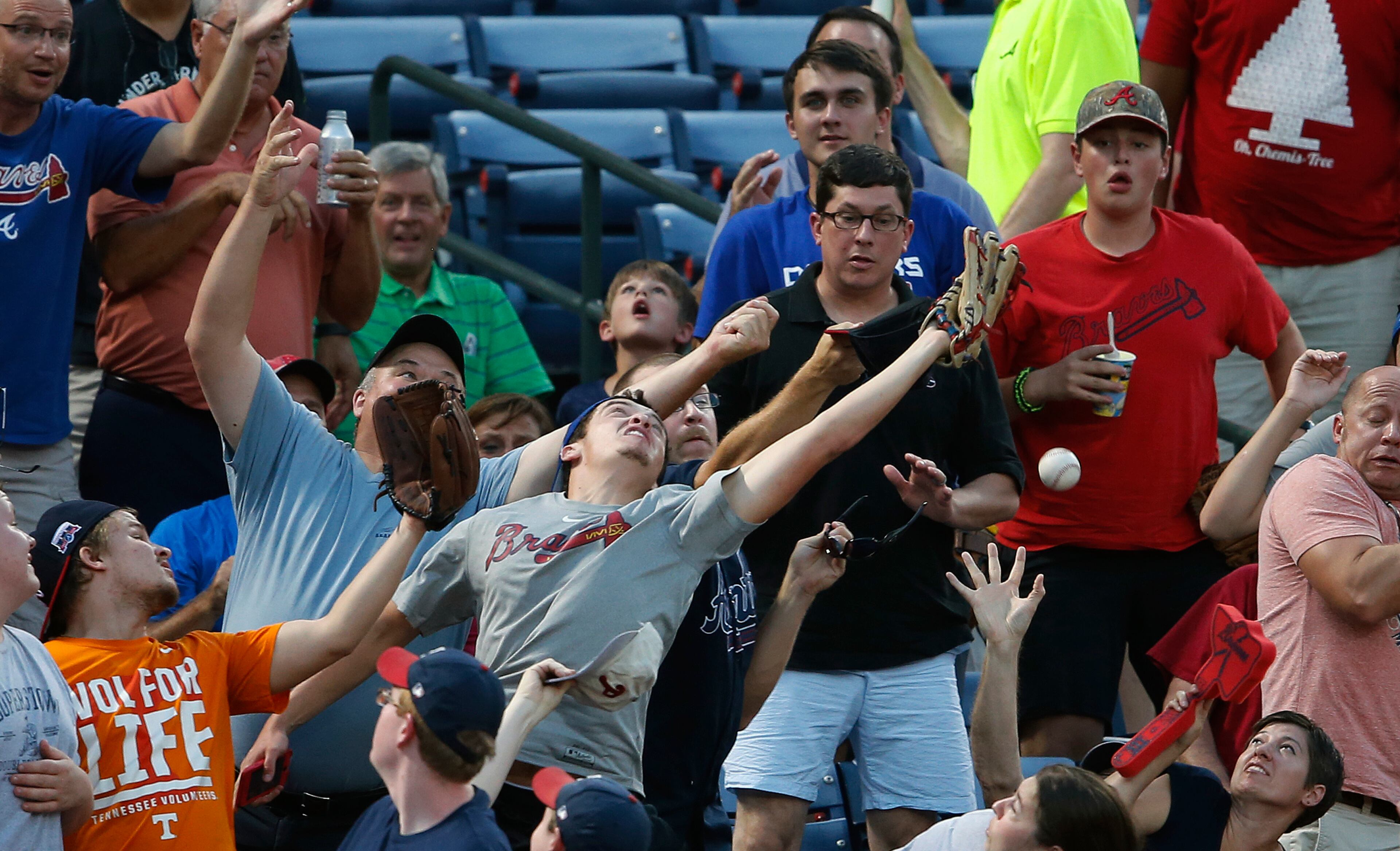 Fans reach for a foul ball during a baseball game between the Atlanta Braves and the Philadelphia Phillies, Friday, July 29, 2016, in Atlanta. (AP Photo/John Bazemore)