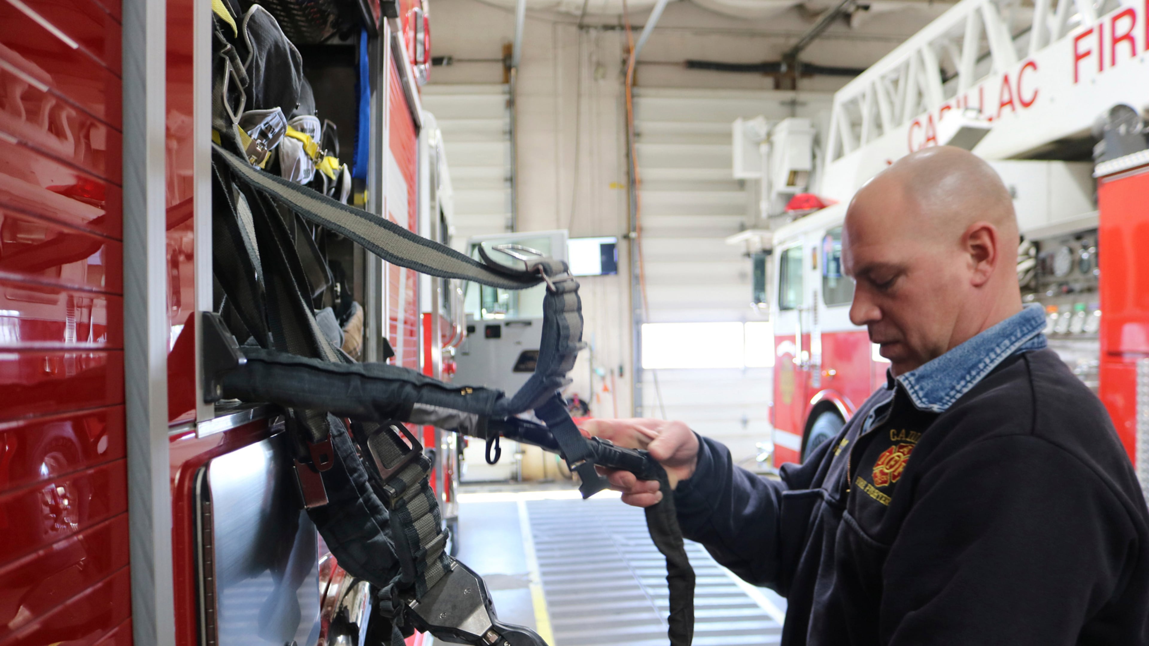 FILE - Cadillac firefighter/paramedic Joe Barron does an equipment check on an air pack on one of the trucks during some downtime, March 12, 2021 in Cadillac, Mich. (Rick Charmoli /The News via AP, file)