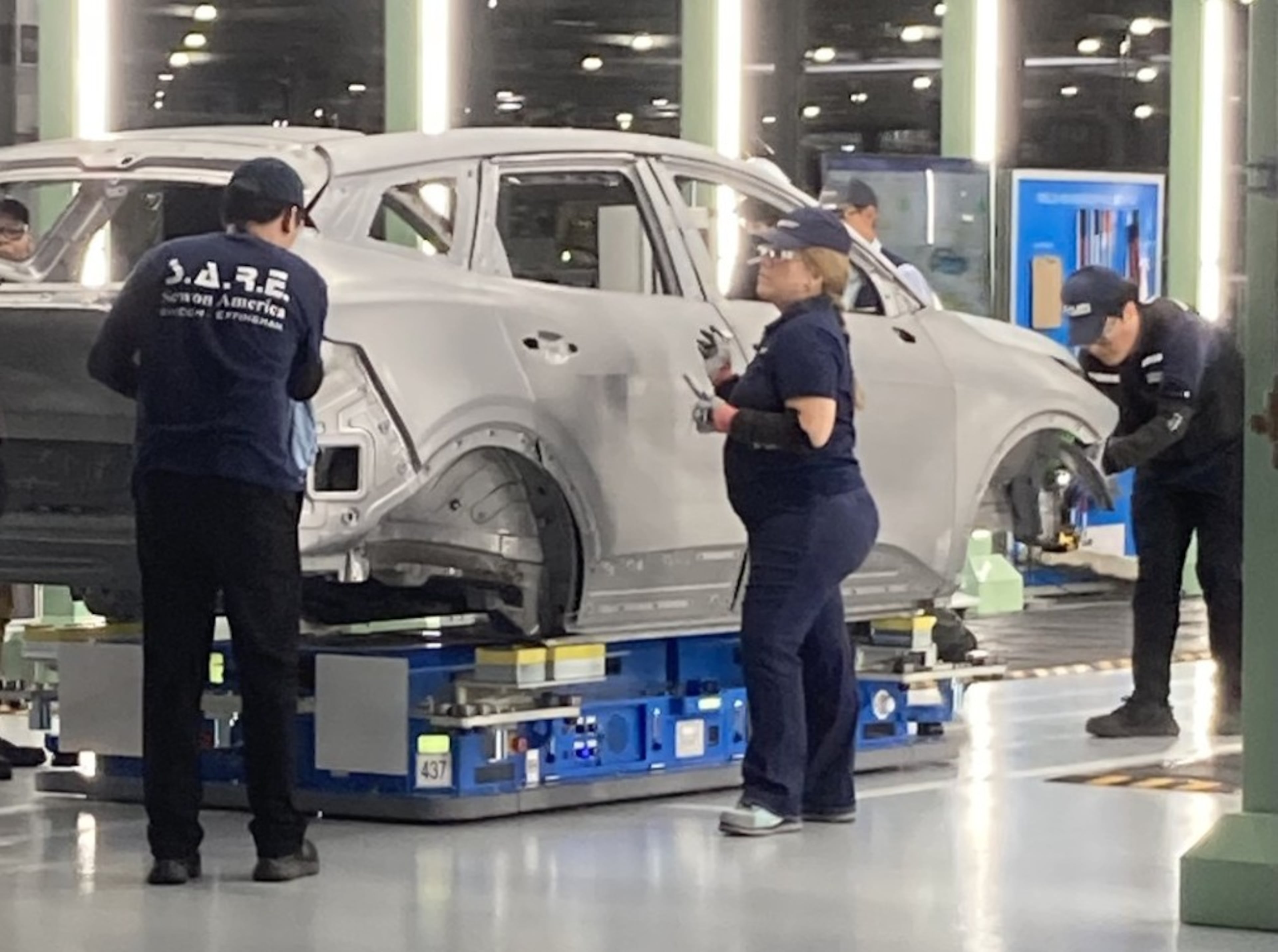 Hyundai factory workers, known as metapros, inspect a Kia Sportage hybrid autobody during the manufacturing process in June at the Hyundai Metaplant near Savannah. (Adam Van Brimmer/AJC)