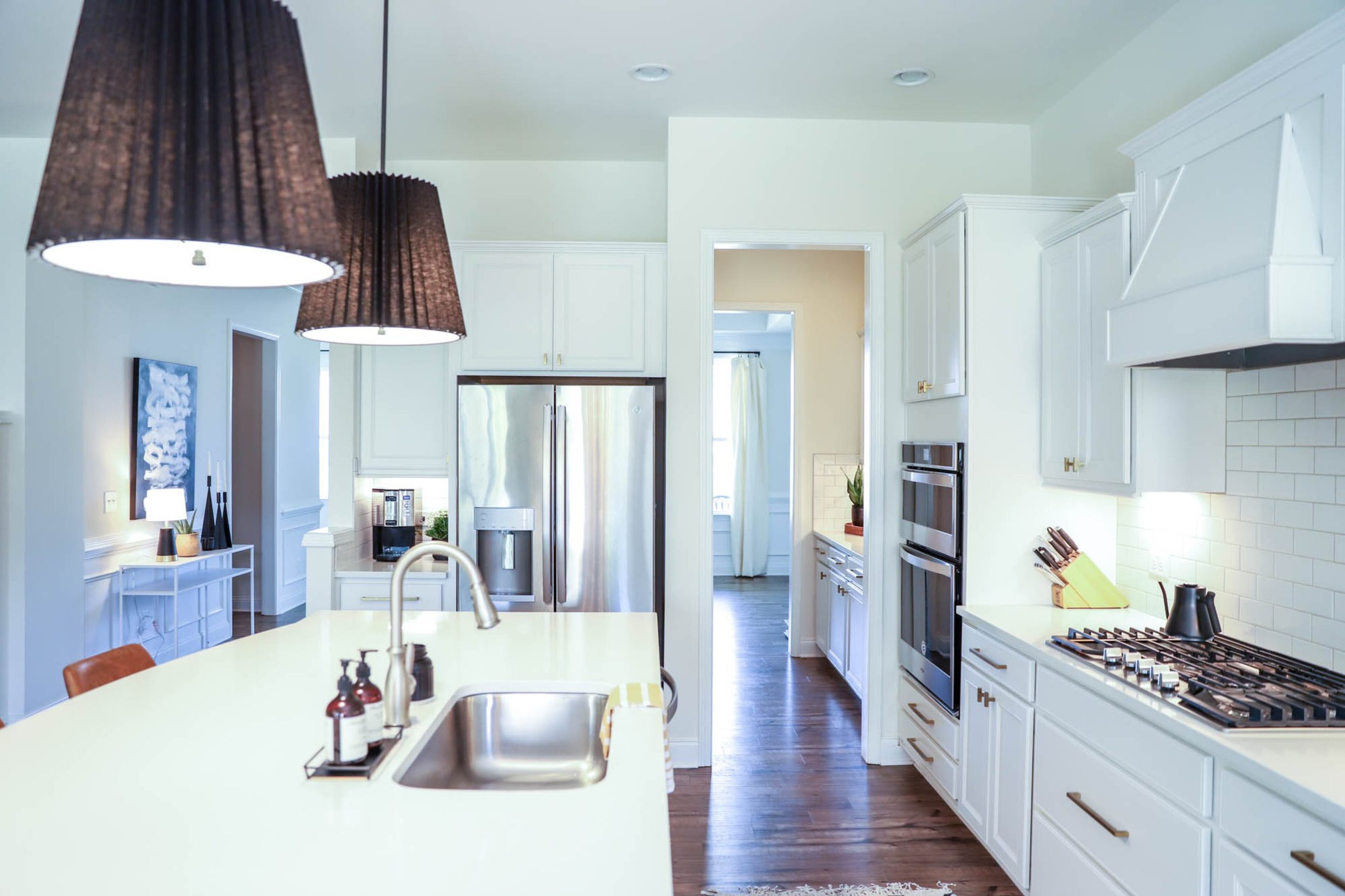 Barton 18-inch pleated drum pendants from Rejuvenation stand out starkly against the quartz countertops white subway tile of Shelly and David McIntosh’s kitchen, achieving a stylish contrast. Text by Shannon Dominy. Photo by Reynolds Rogers.