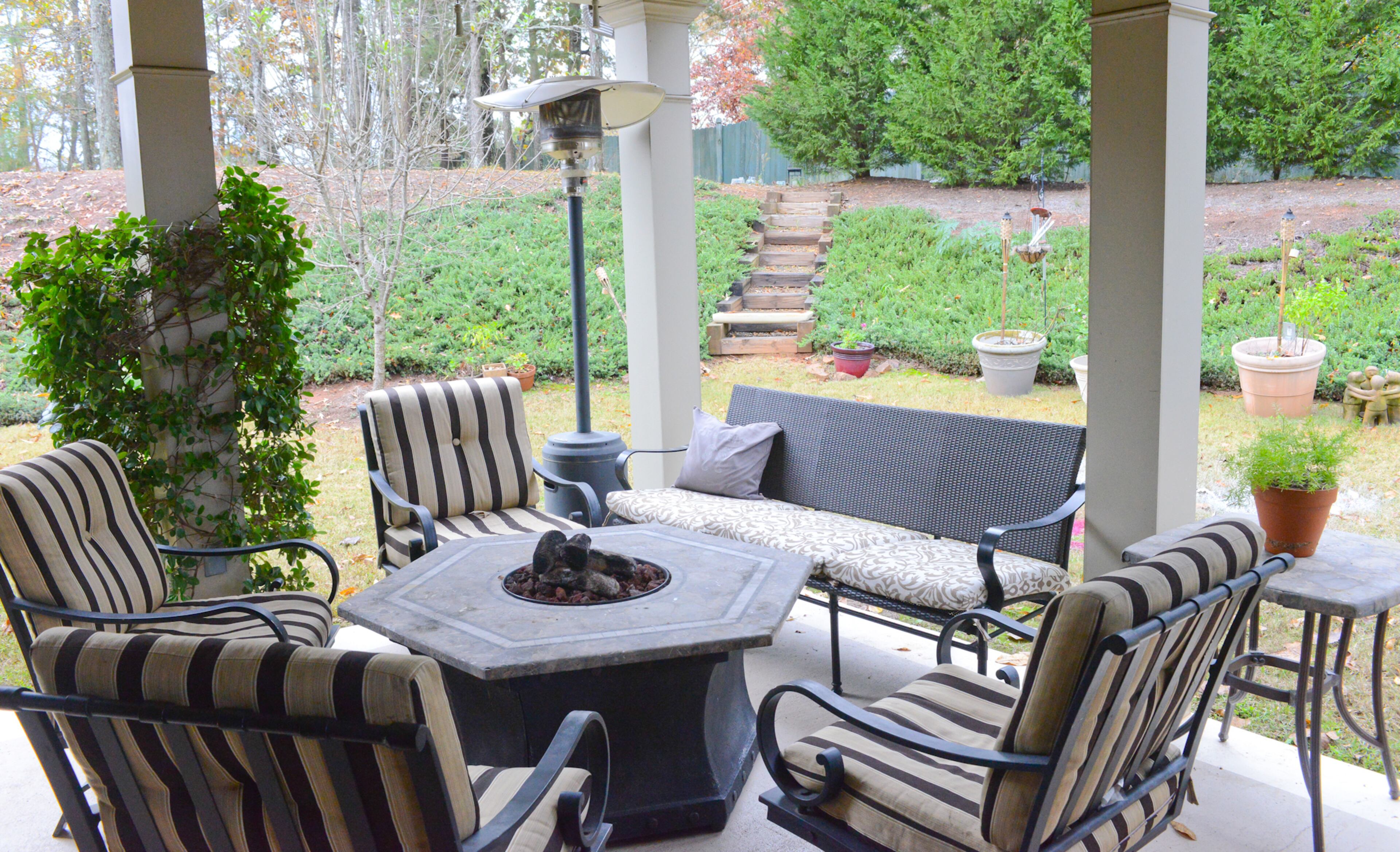 Ken, Stephanie and Geneva Wright enjoy using the covered porch outside of their breakfast area in their Cumming home. The porch overlooks the wooded backyard and includes an outside television, seating area and a fire pit.