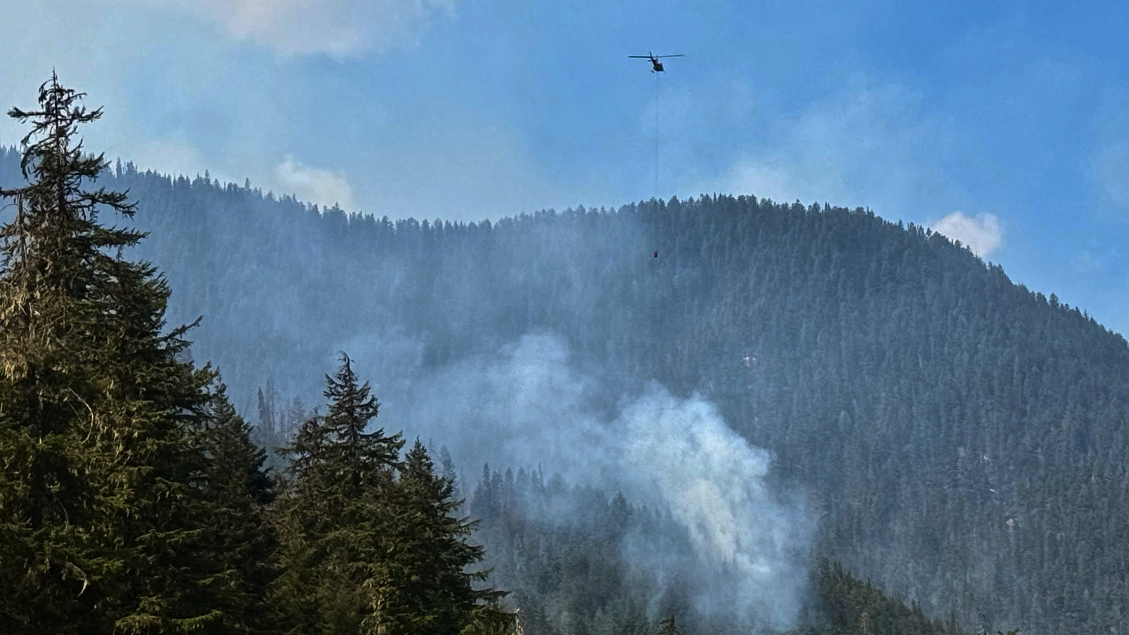 Fire crews drop water on a wildfire along Highway 3 in Manning Park, British Columbia, as fires burn throughout the southeastern part of the Provence on Wednesday, Aug. 12, 2026. (AP Photo/Haven Daley)