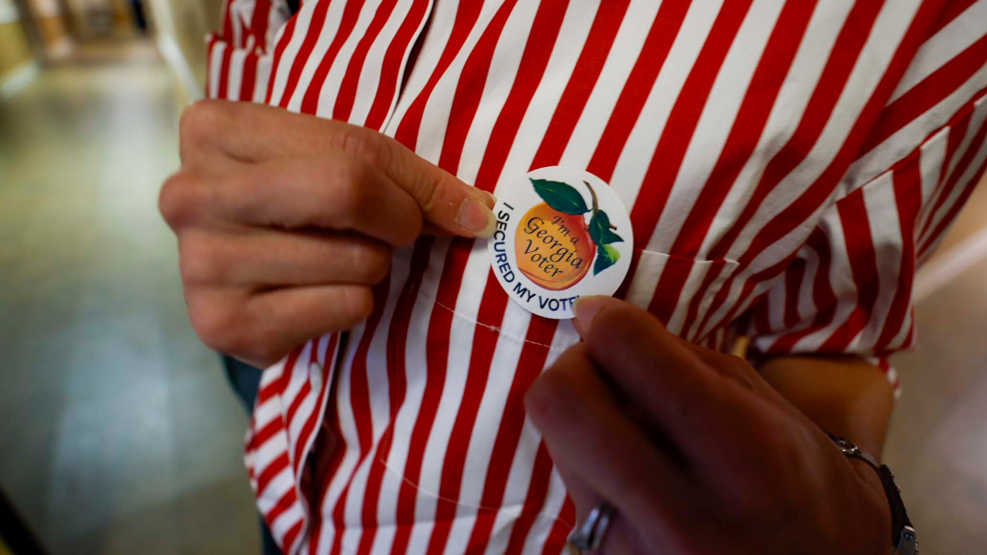 A Georgia voter puts on her voting sticker after casting her ballot. Georgia Secretary of State Brad Raffensperger is set to remove nearly 500,000 voter registrations from the state's rolls. Officials say the registrations largely reflect people who have changed addresses, but voting rights activists say it threatens legitimate voters. (Miguel Martinez/AJC)