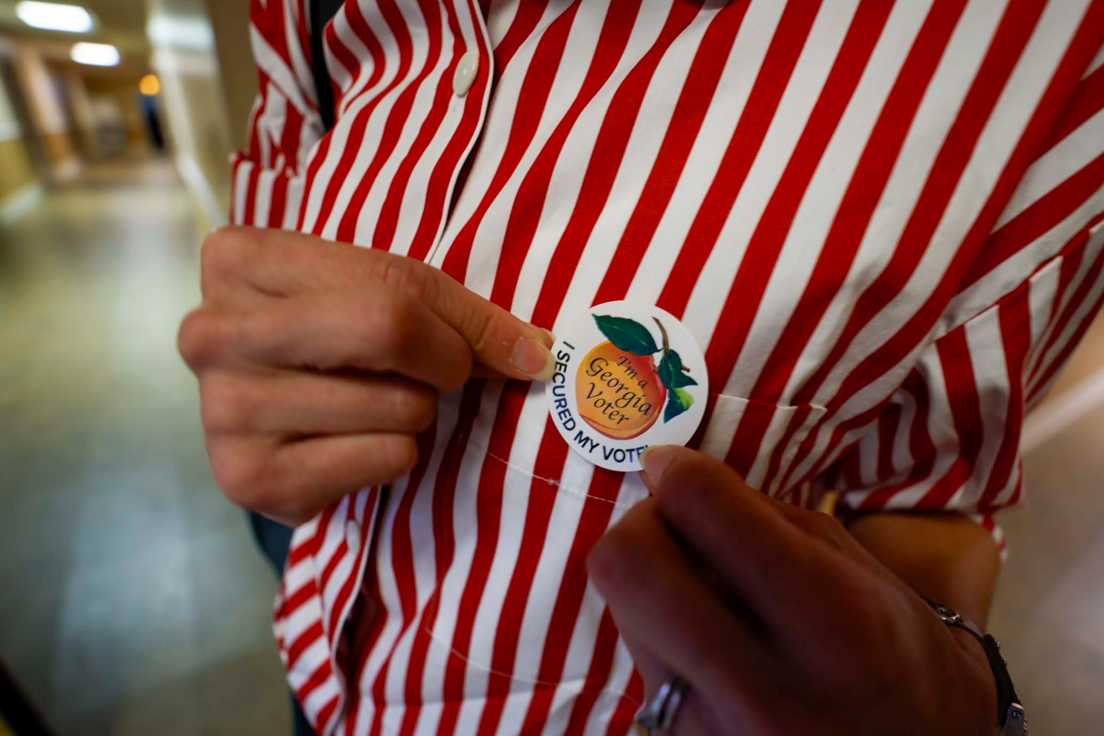 Tamara Lamia puts on her voting sticker after casting her ballot at the Israel Baptist Church in Kirkwood during the Georgia Public Service Commission’s special election at Ron Anderson Community Center in Cobb County on Tuesday, June 17, 2025. (Miguel Martinez/AJC)