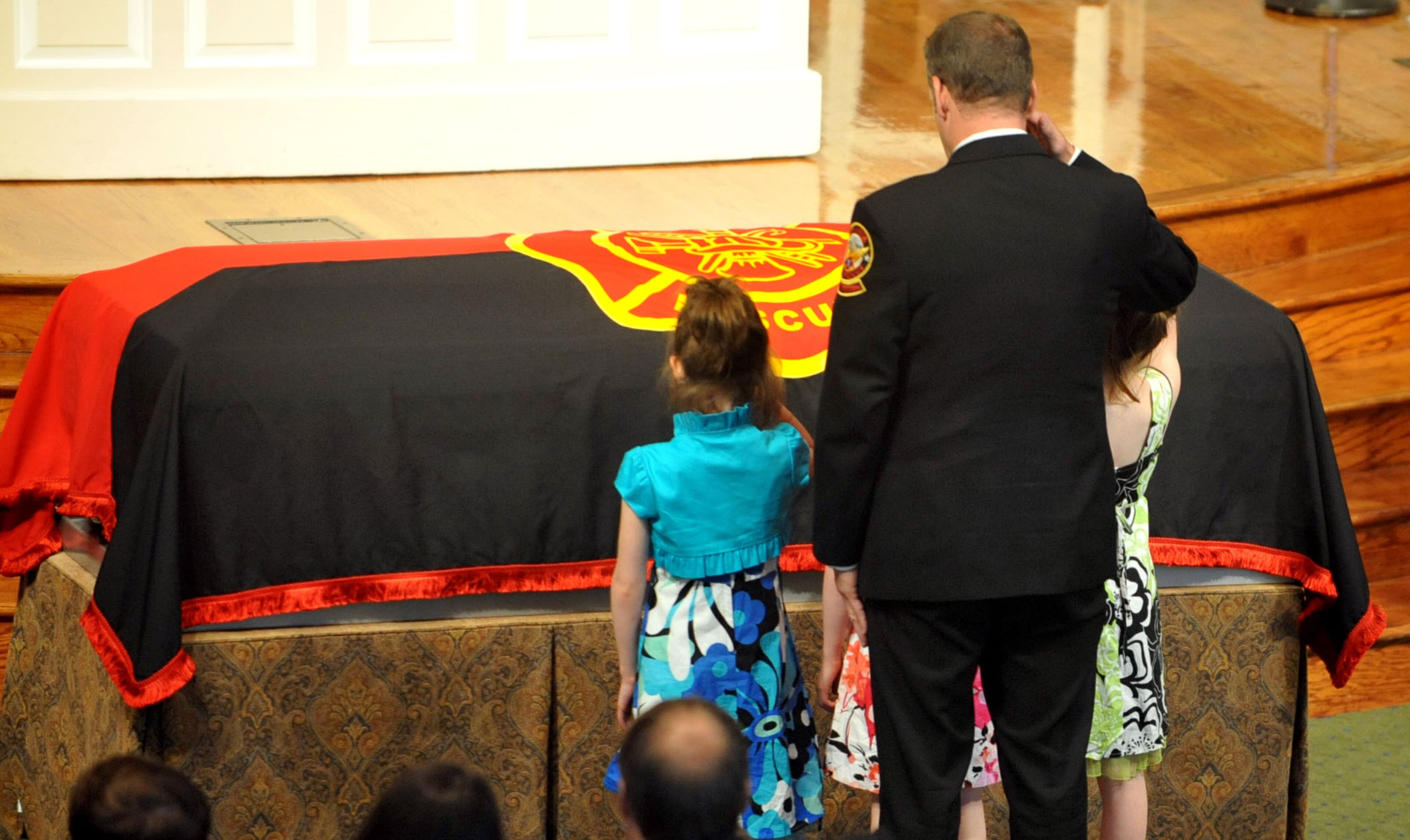 Sgt. Guinn's daughters, Makenna, Alyssa, and Isabelle, assisted by AFR Lt. Brian Garner, salute their dad.