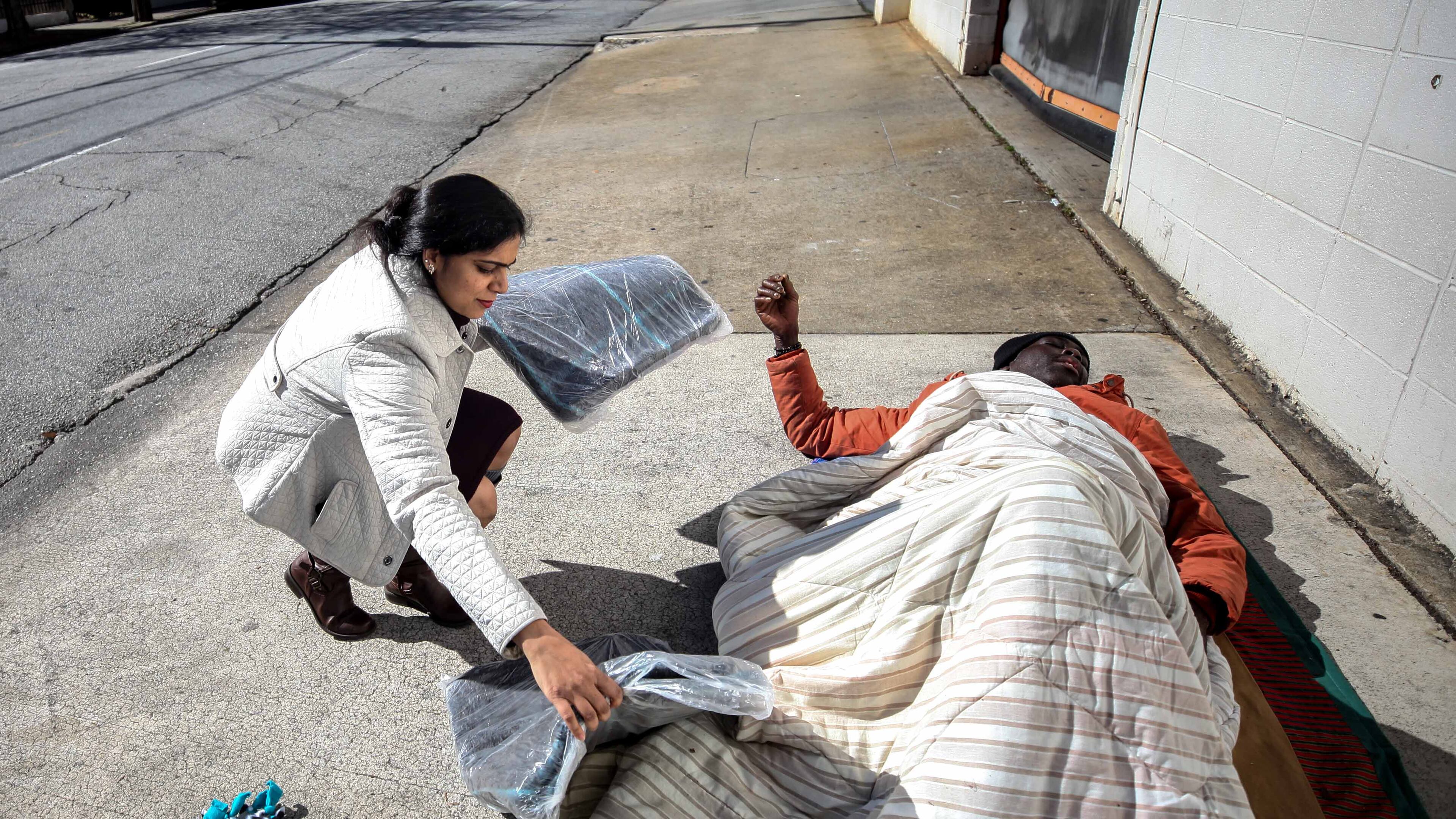 Pictured is Archita Ghosh laying a blanket near a homeless man on Ellis Street in Atlanta in 2019. The pandemic of 2020 has resulted increased homelessness that as spread to north Fulton. BRANDEN CAMP/SPECIAL