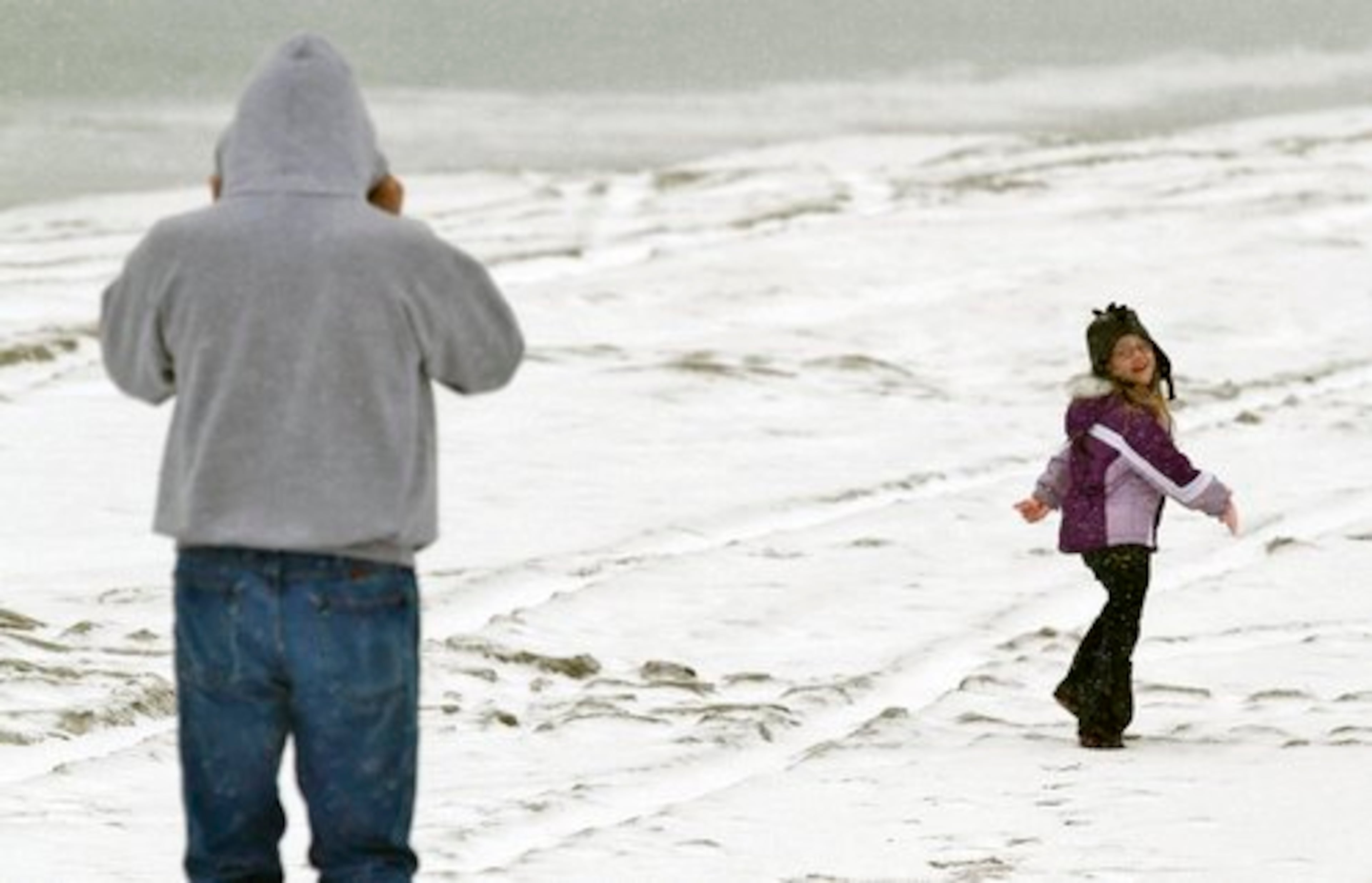 Leigha Gargani, 5, looks back to her grandfather Jim Rose both of Hubert, N.C. as they enjoy the snowfall on the beach near the Bogue Inlet Fishing Pier, Saturday, Jan. 22, 2011 in Emerald Isle, N.C.