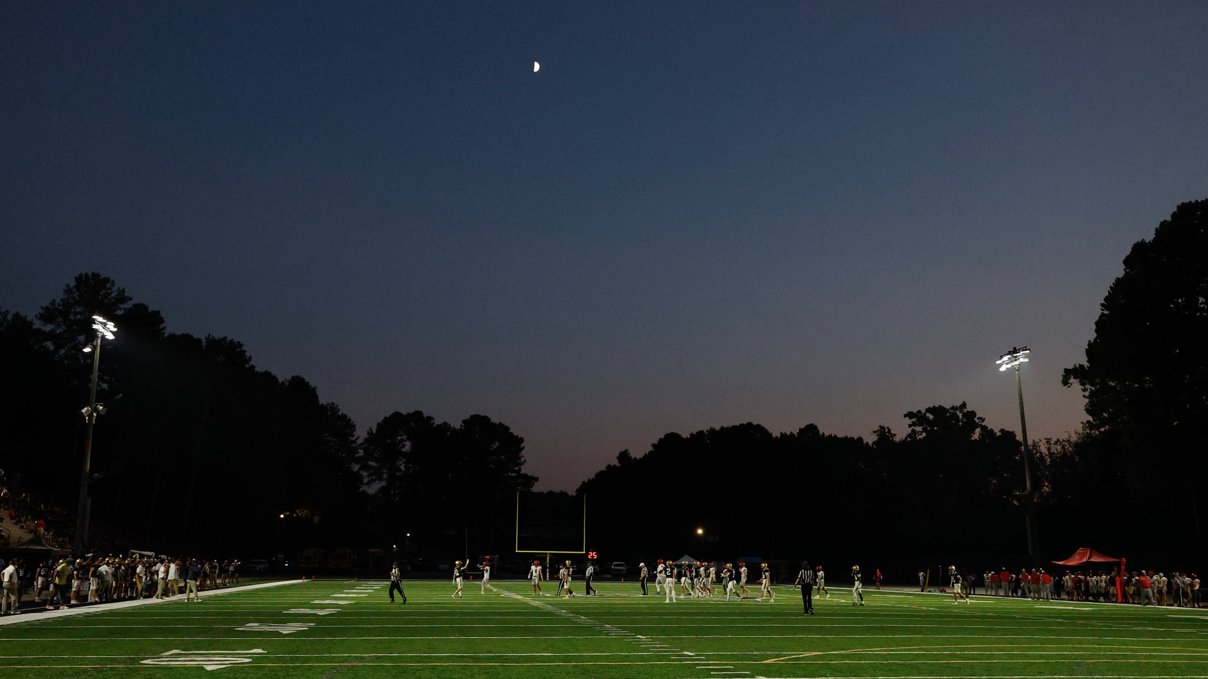 Teams play under a first quarter moon during the first half a high school football game between Winder-Barrow and St. Pius X, Friday, Sept. 18, 2026, in Atlanta. (Erik S. Lesser for the AJC)