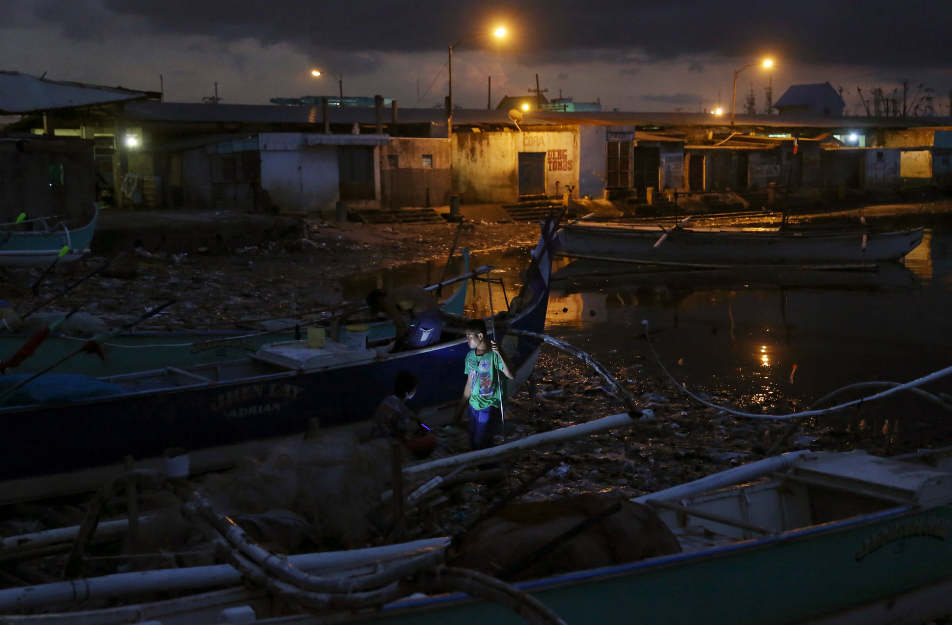 REPAIR WORK--A Filipino fisherman joins others as they work on the repairs of their boat at a coastal village in Navotas, north of Manila, Philippines Monday, March 23, 2015. (AP Photo/Aaron Favila)