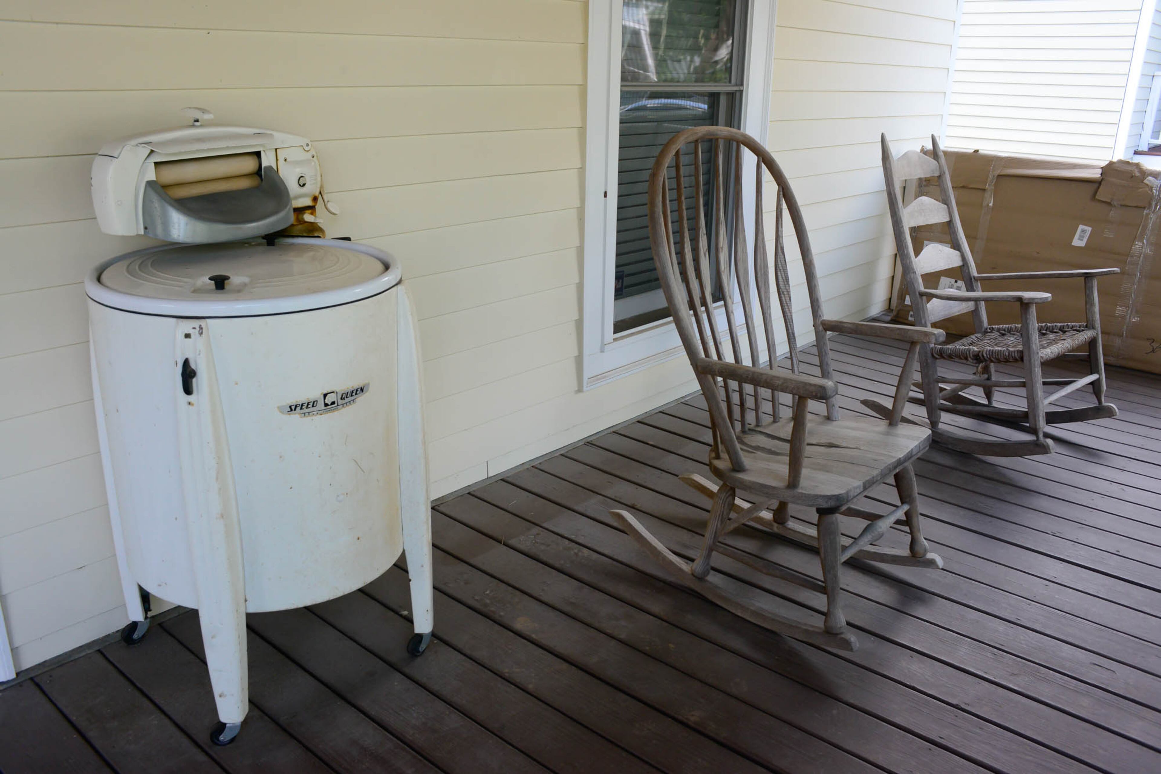On the front porch, homeowners Nash and Kevin Gillese use a vintage washing machine, originally purchased by Nash's aunt, as a cooler for parties. Two rocking chairs were left by the home's previous owners.