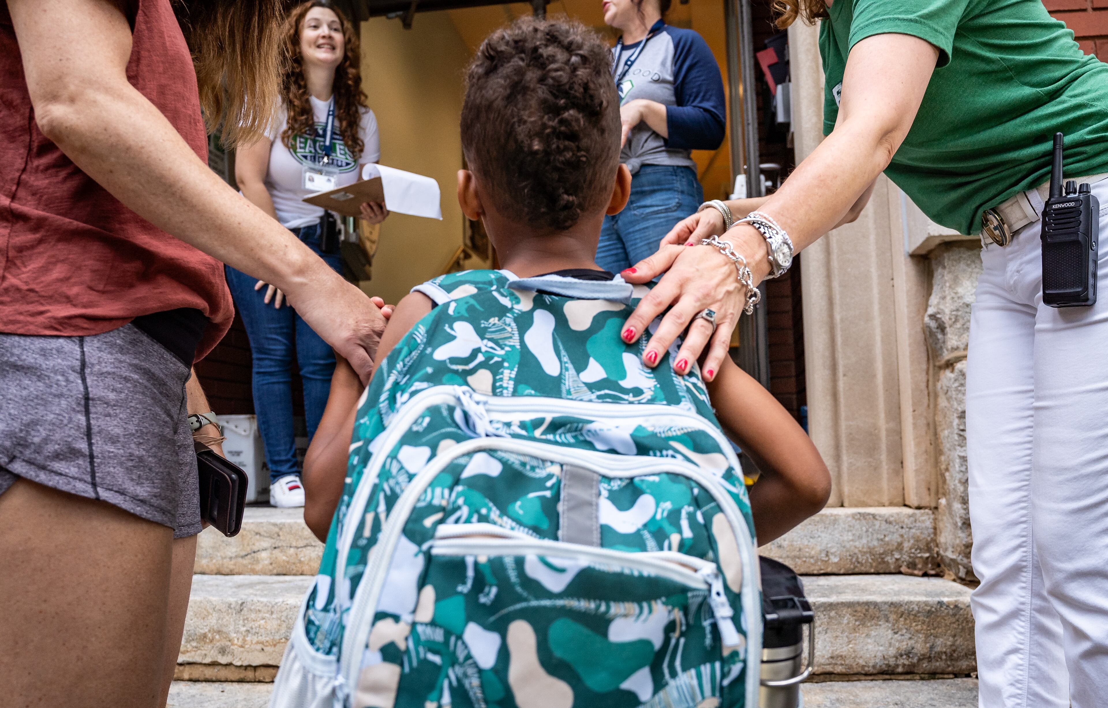 A student is led into Glennwood Elementary School in Decatur on the first day of school on Tuesday, July 30, 2024. (Seeger Gray / AJC)