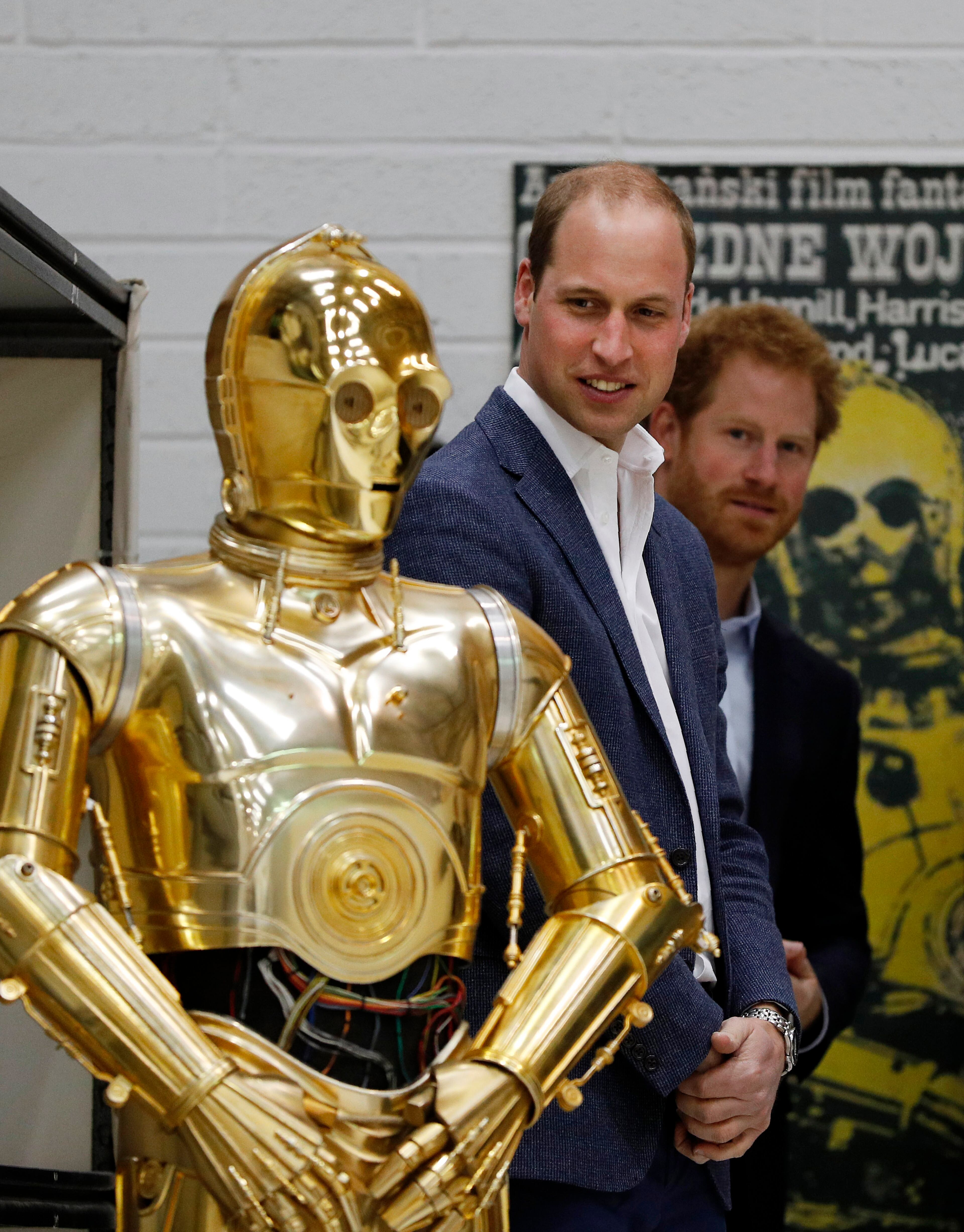 IVER HEATH, ENGLAND - APRIL 19: Prince William, Duke of Cambridge (C) and Prince Harry (R) look at the droid C3P0 from Star Wars as they visit the creature and droid department at Pinewood studios on April 19, 2016 in Iver Heath, England. Prince William and Prince Harry are touring Pinewood studios to visit the production workshops and meet the creative teams working behind the scenes on the Star Wars films. (Photo by Adrian Dennis-WPA Pool/Getty IMages)