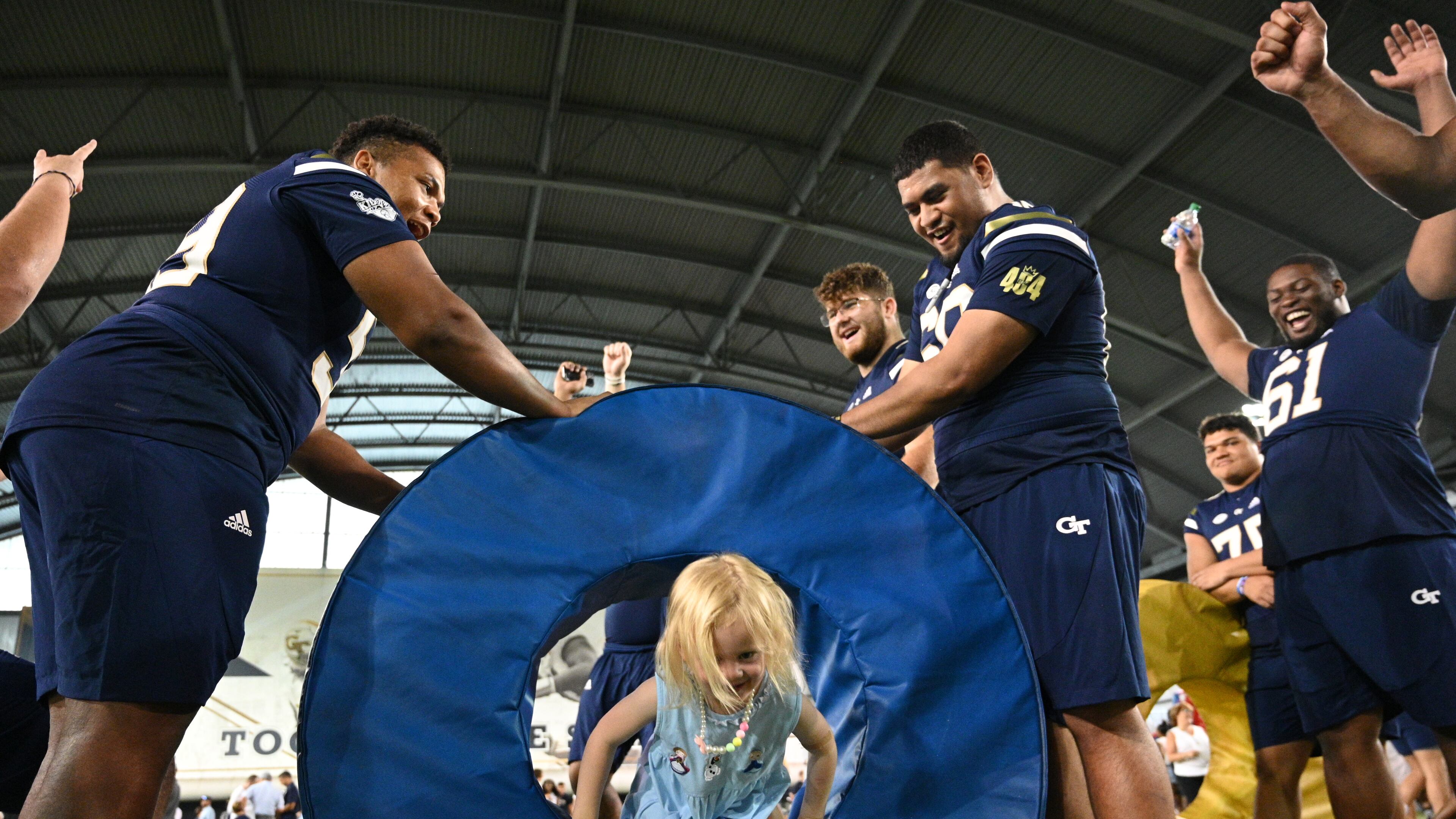 Harper Key, daughter of Tech coach Brent Key, has fun with some players during First Saturday on The Flats in 2022. (Hyosub Shin / Hyosub.Shin@ajc.com)