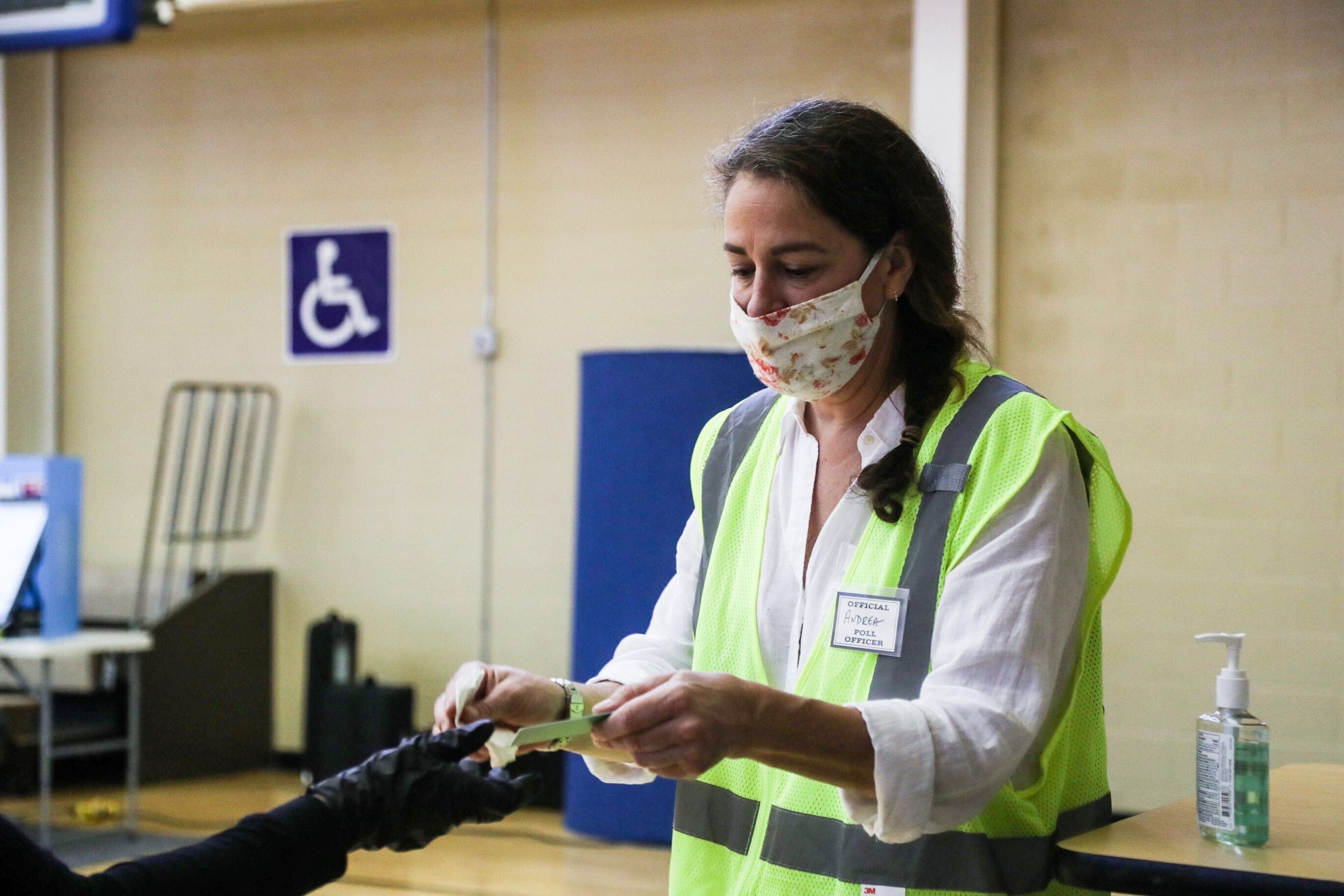 Poll clerk Andrea Keener sanitizes the electronic ballots and stylus pen after voters used them to cast their ballot at the Smyrna Community Center.