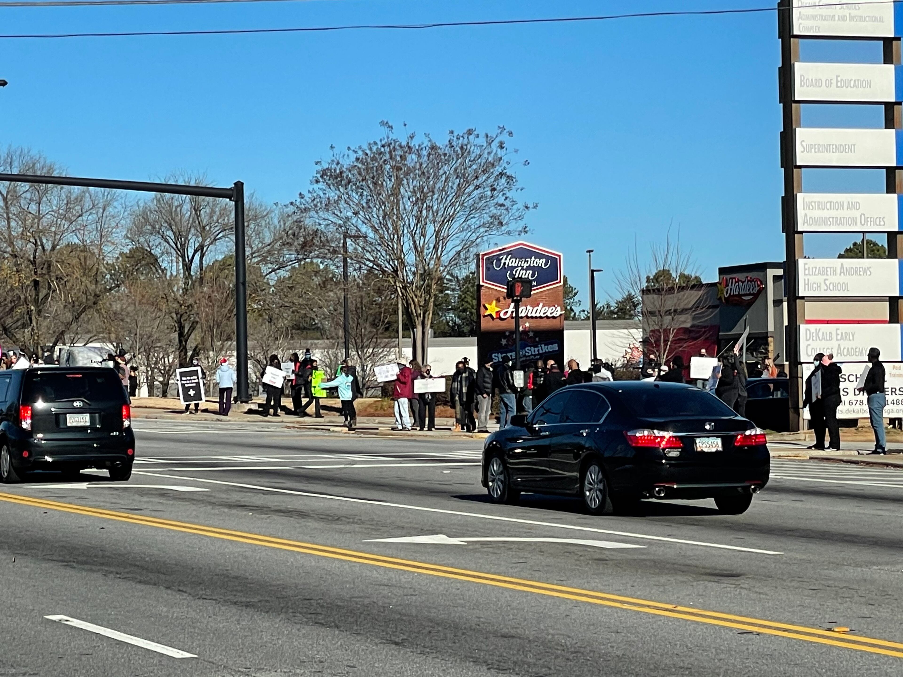 Community members in DeKalb held signs on Tuesday to protest against the reopening of DeKalb County schools.