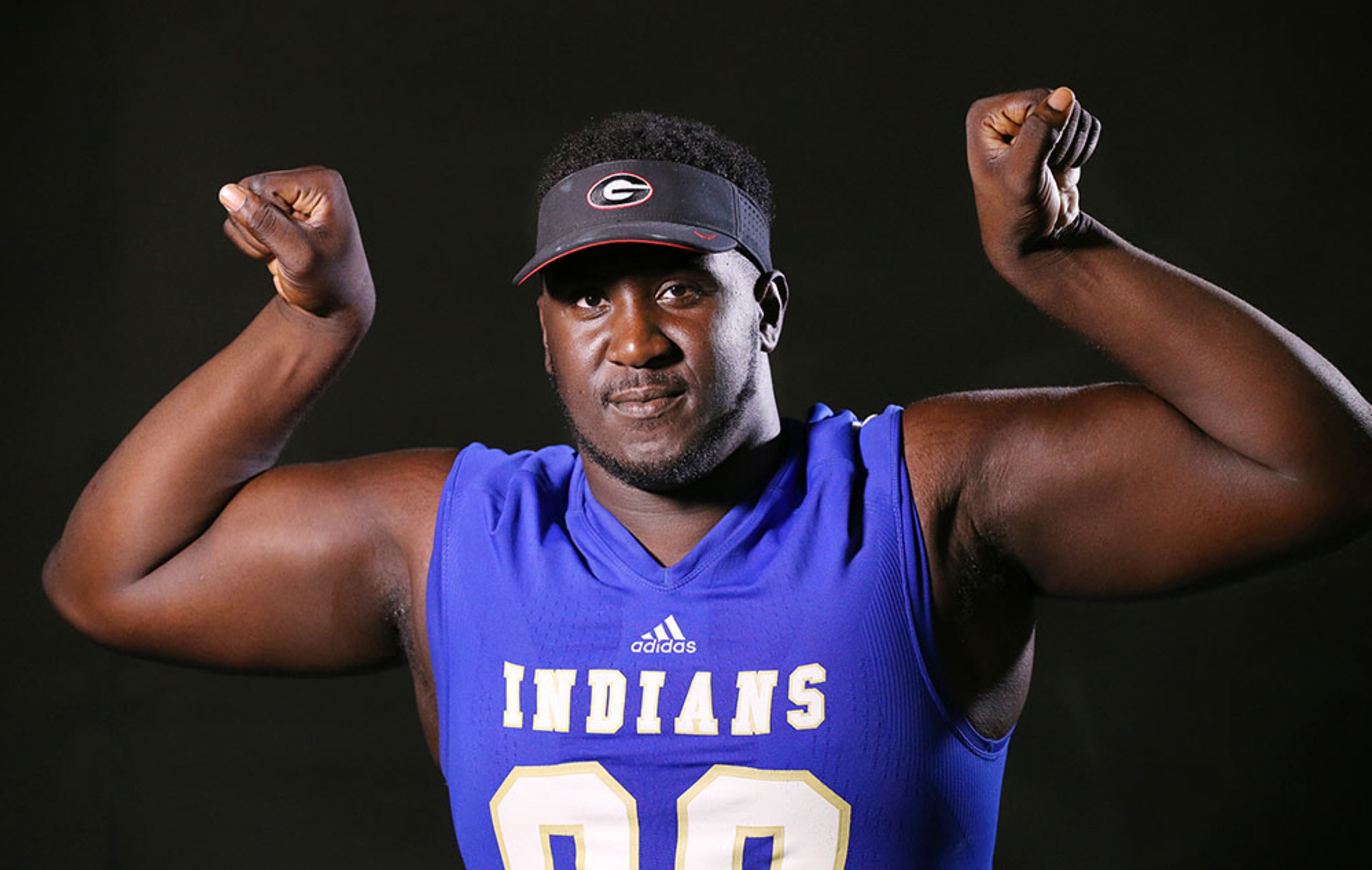 McEachern High School defensive tackle Julian Rochester flexes, but only after putting on his Georgia hat, for his AJC Super 11 portrait.