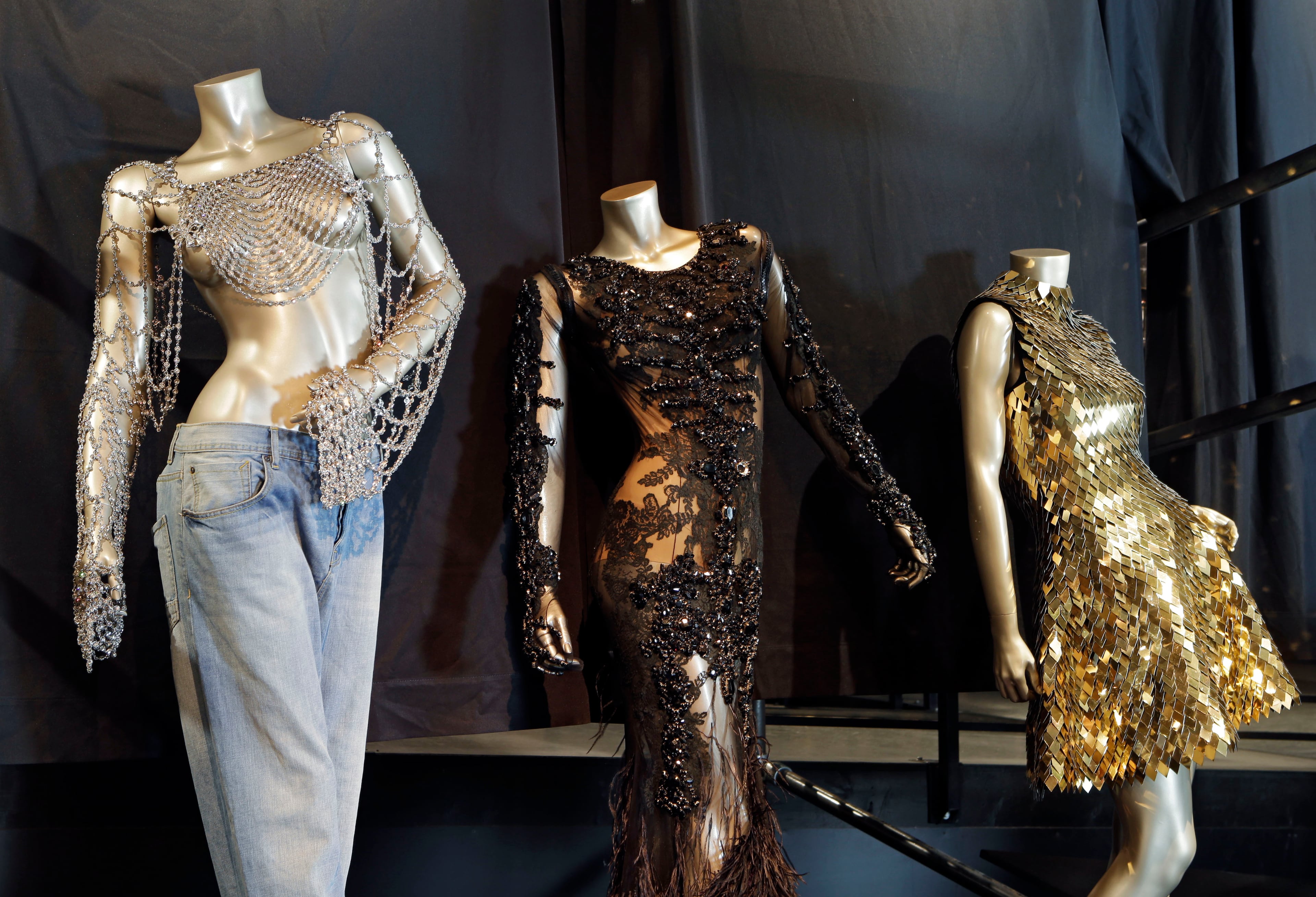 In this Thursday, July 17, 2014 photo, from left, outfits from Beyonce's 2003 "Dangerously in Love," 2012 "Met Gala" and 2011 "Run the World (Girls)" are shown in a new exhibit at the Rock and Roll Hall of Fame in Cleveland. The Rock Hall announced Friday, July 18, 2014, that outfits from Beyonce's Super Bowl performance and music videos will debut Tuesday in the Ahmet Ertegun Main Exhibit Hall in its Legends of Rock section next to iconic pieces from Michael Jackson, David Bowie and Bruce Springsteen. (AP Photo/Mark Duncan)