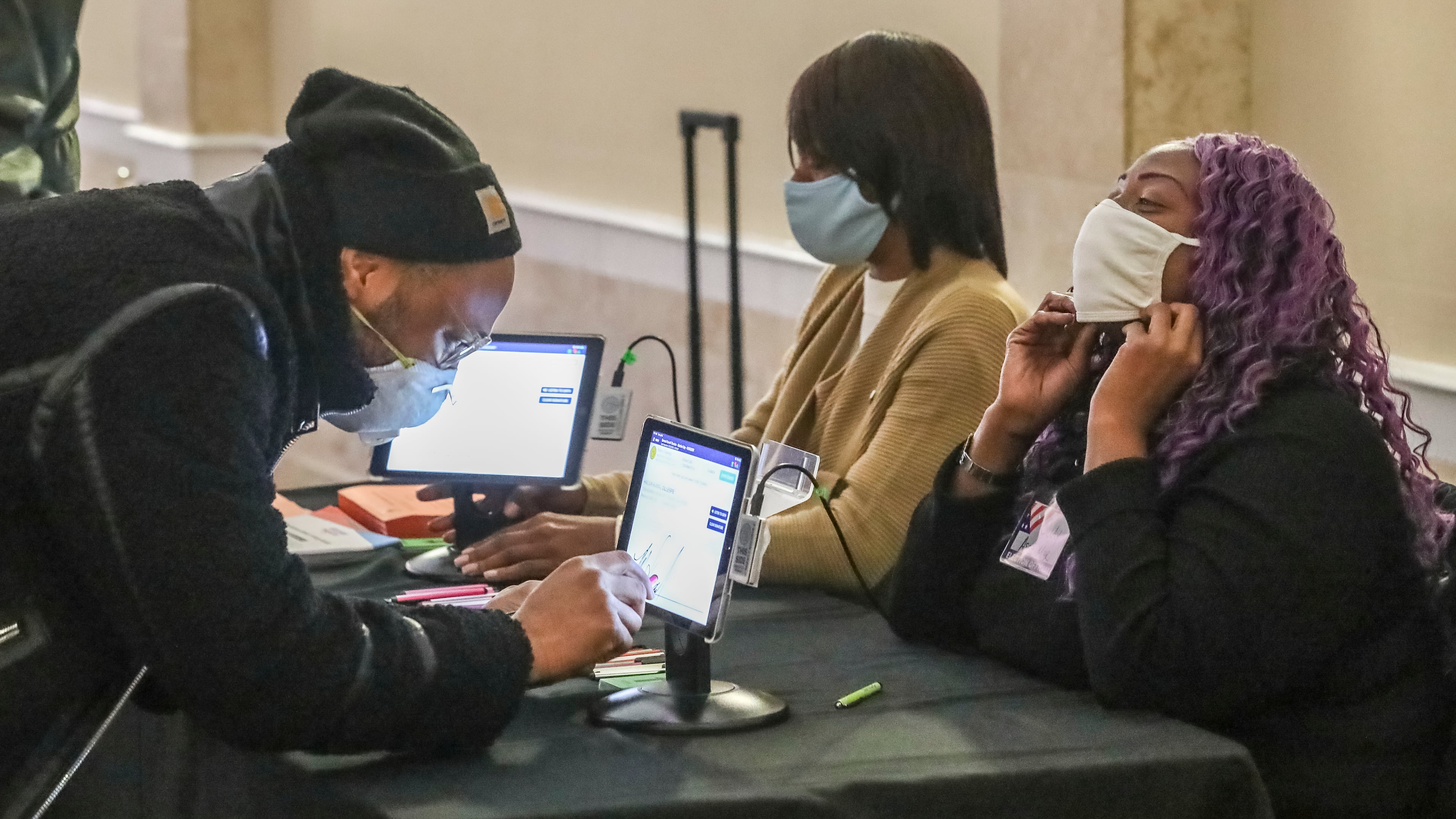 January 5, 2021 Atlanta: Kamal Gillespie (left) verifies his voter I.D. information to poll workers Brandy Allen (center) and Cuedriene Edwards (right) on Tuesday, Jan. 5, 2021 at the Park Tavern located at 500 10th St NE in Atlanta. Georgia’s long moment in the national spotlight culminated Tuesday, Jan. 5, 2021, when state voters cast their votes to determine which party would control the U.S. Senate. Georgia voters also voted to elect a member of the state Public Service Commission, which regulates energy and utility rates and issues. The two most expensive Senate races in history saw more than $833 million been spent by the four campaigns and outside groups supporting them, blanketing the airwaves and stuffing mailboxes across the state. Much of that money has come from organizations with no direct connection to Georgia. (John Spink / John.Spink@ajc.com)