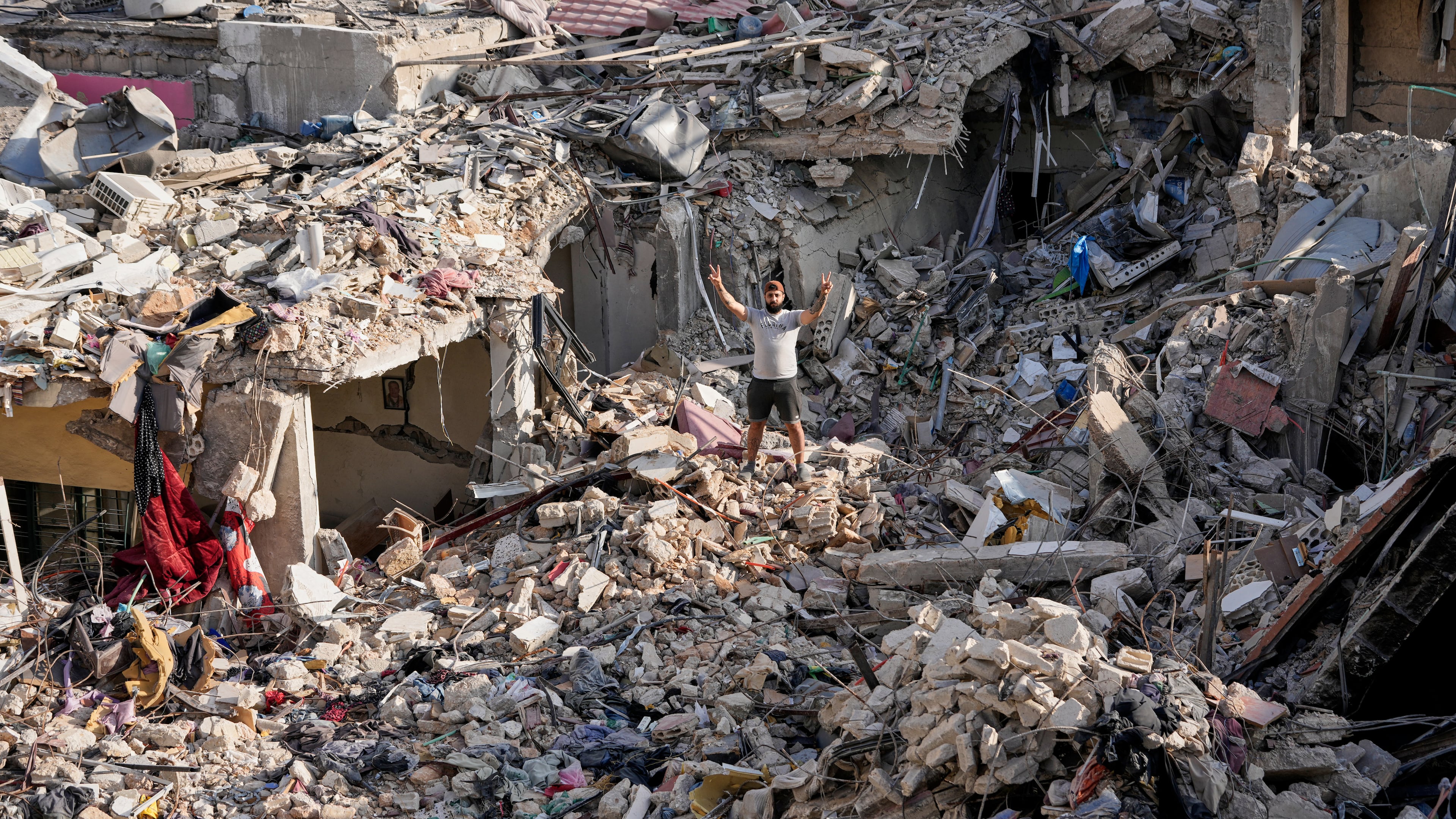 A man who returns to his village following the announcement of an initial ceasefire agreement between the United States and Iran, flashes victory sign as he stands on the rubble of his destroyed house in Nabatiyeh town, southern Lebanon, Tuesday, June 16, 2026. (AP Photo/Hussein Malla)