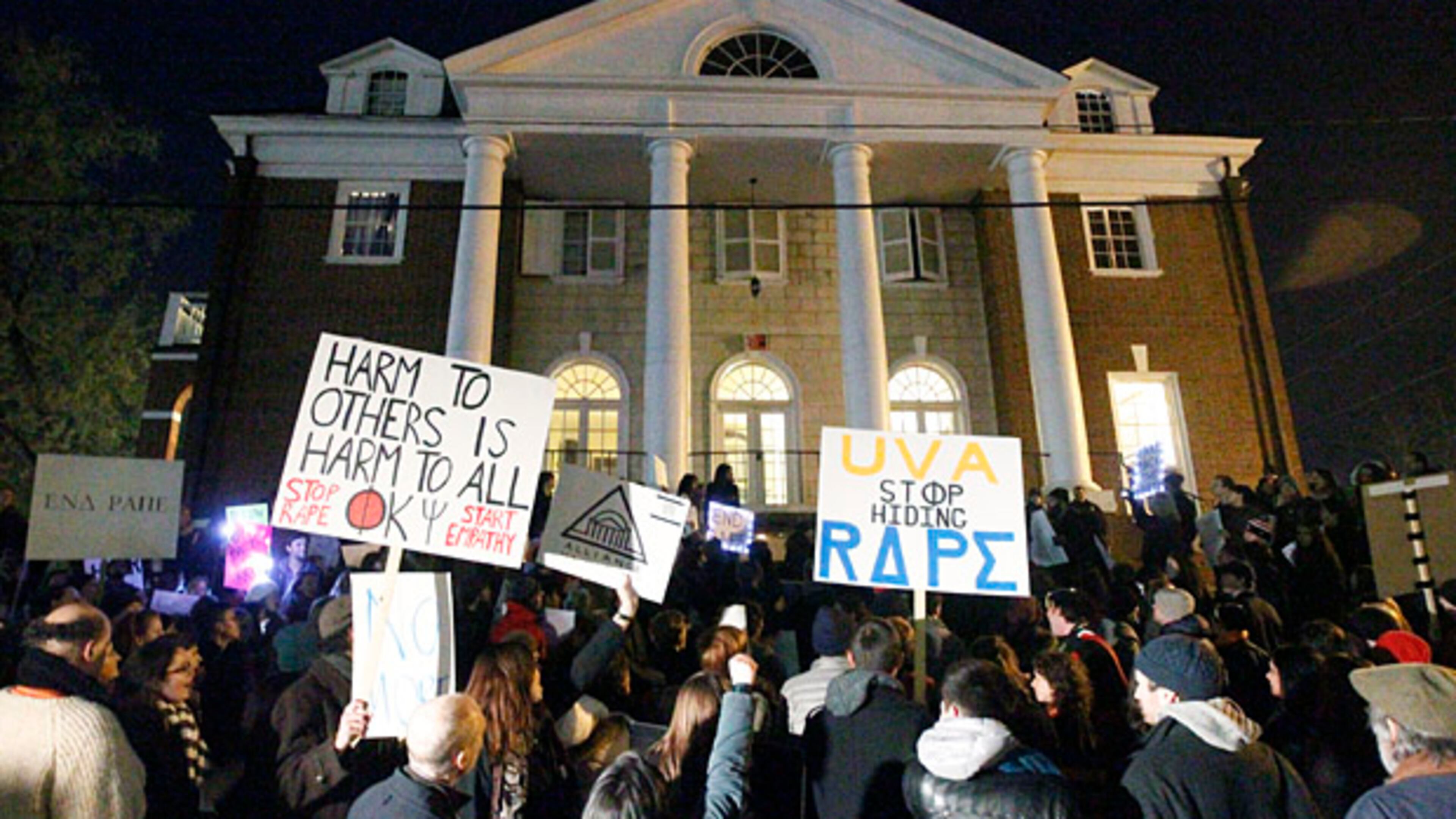 Protestors carry signs and chant slogans in front of the Phi Kappa Psi fraternity house at the University of Virginia, Saturday night, Nov. 22, 2014, in Charlottesville, Va. The protest, the most well-attended of several throughout the day, was in response to the university's reaction to an alleged sexual assault of a student revealed in a recent Rolling Stone article. (AP Photo/The Daily Progress, Ryan M. Kelly)
