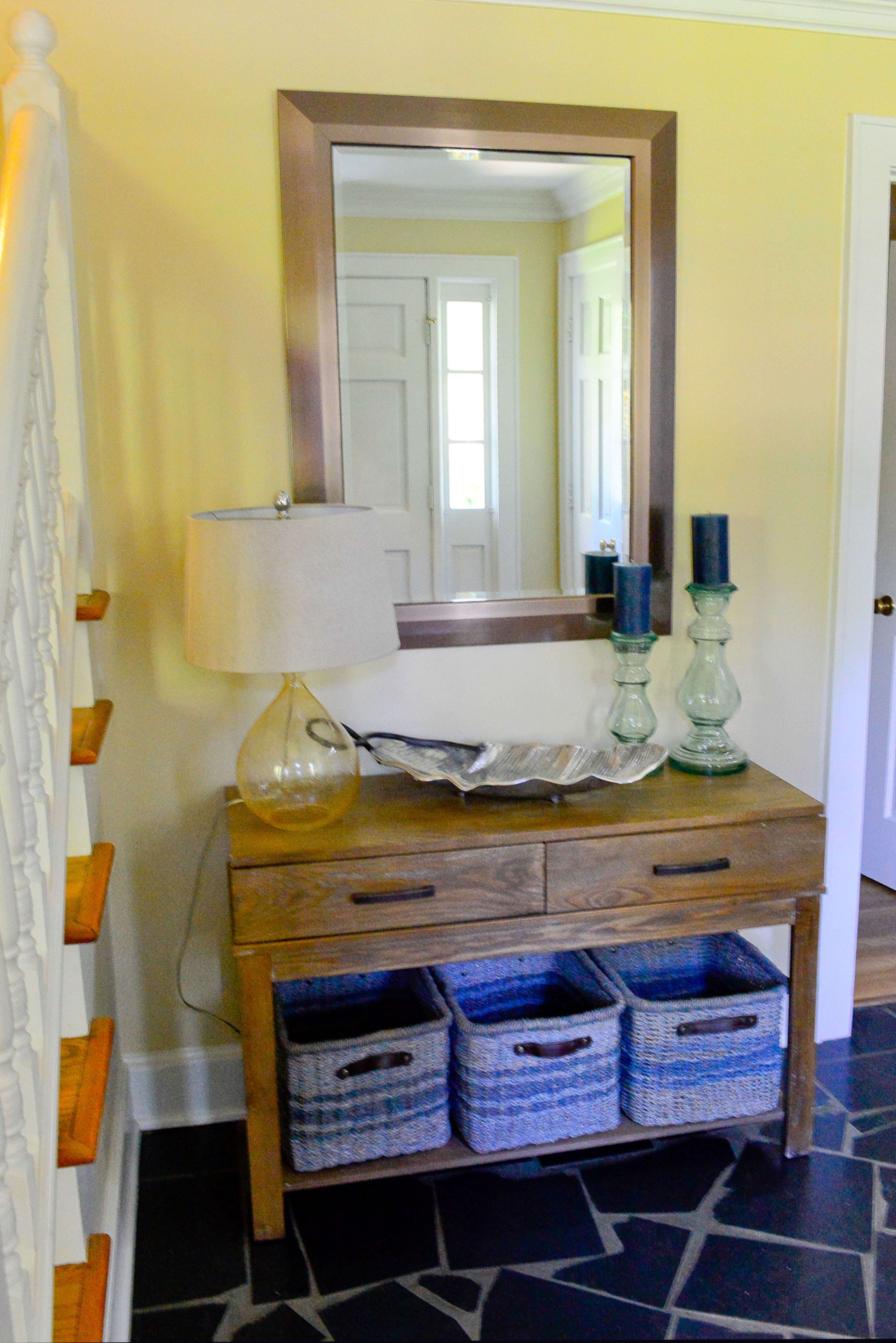 The foyer flooring is slate, with a wood table from HomeGoods and light-toned accessories.