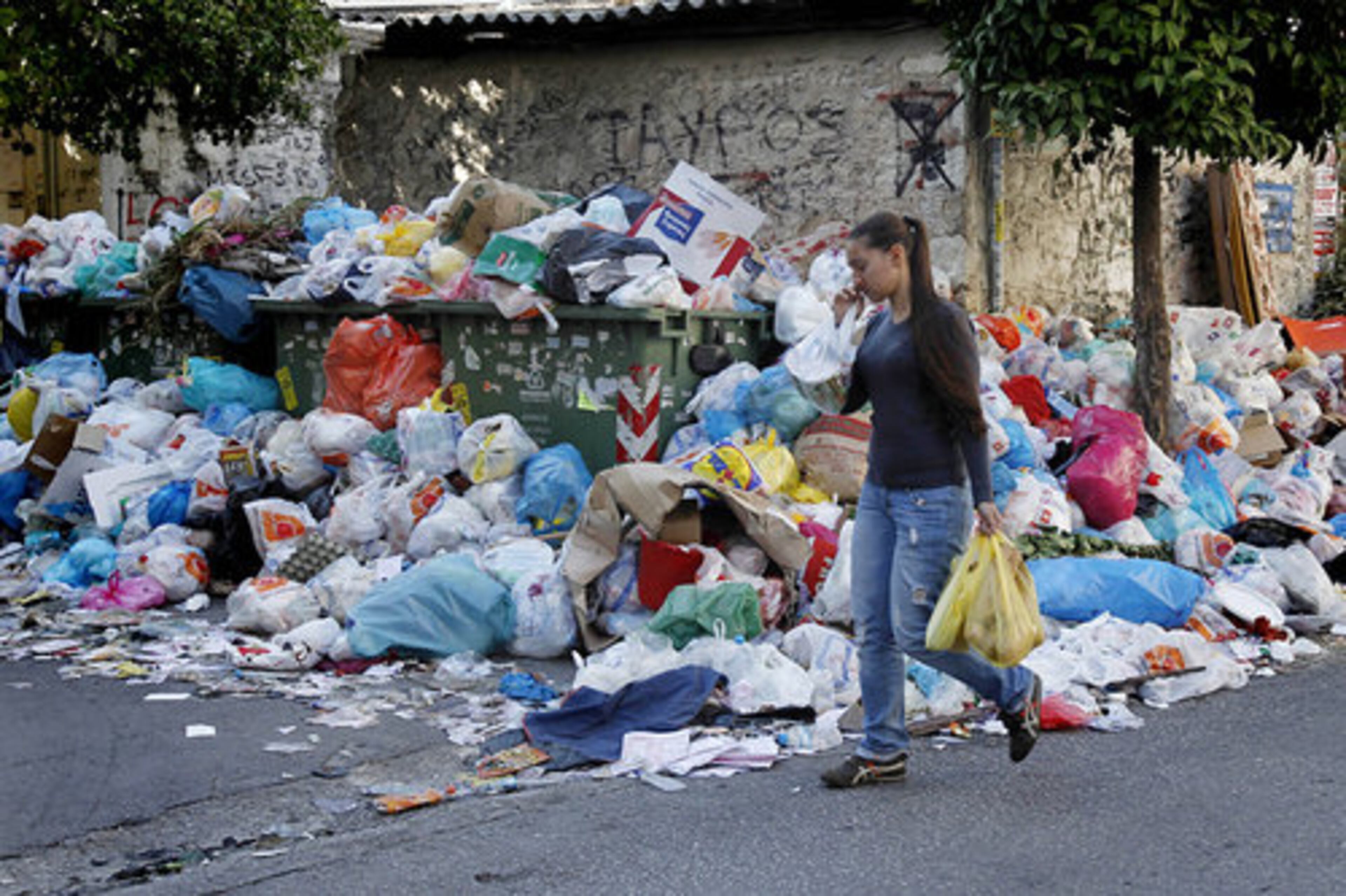 A woman passes a pile of rotting garbage in the Athens on the second day of a general strike that has paralyzed the country and sent tens of thousands of anti-austerity protesters onto the streets. Garbage is overflowing on the streets because garbage collectors have been on strike for two weeks.