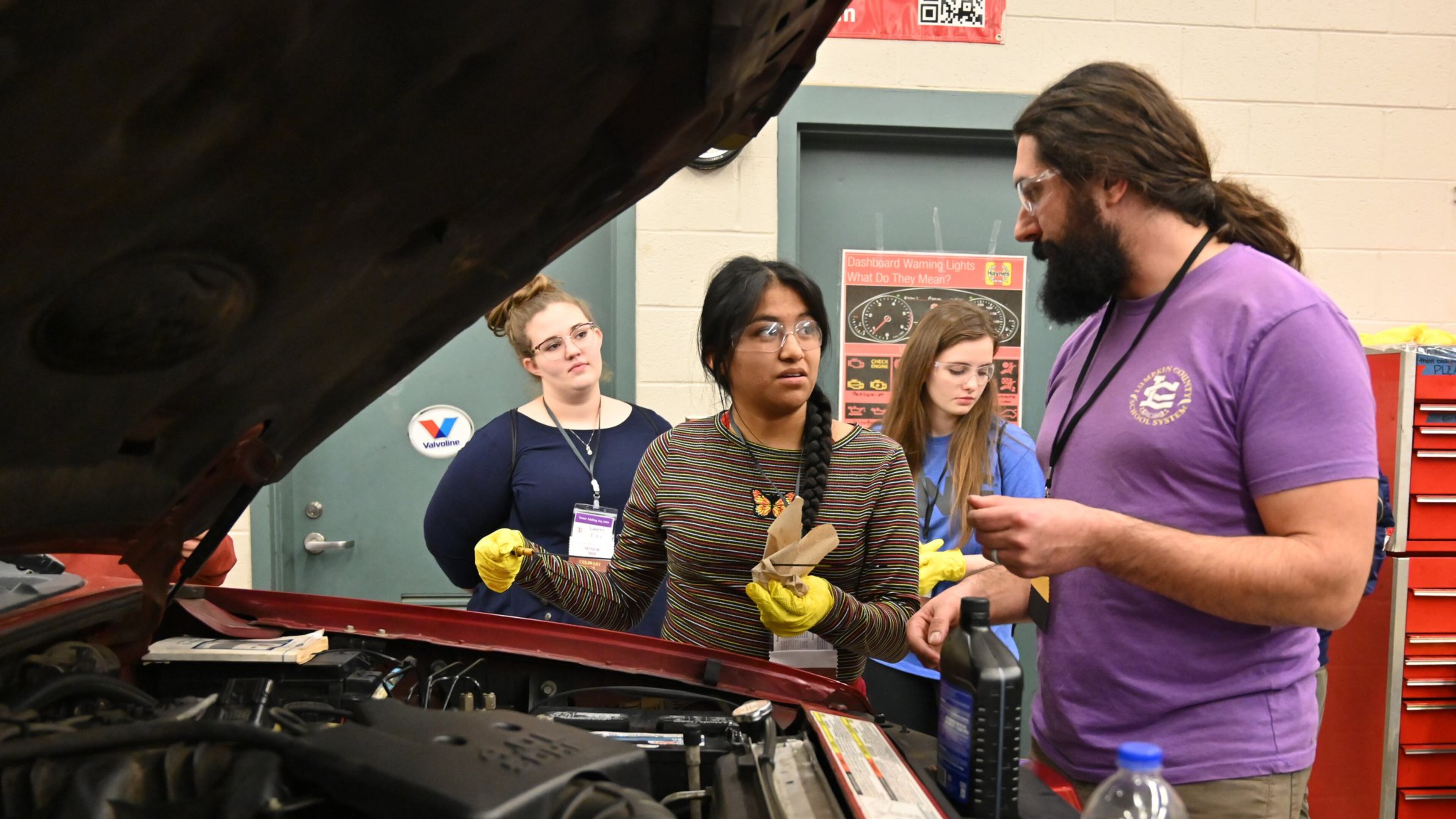 Instructor Jesse Perethian (right) helps senior Erica Ramirez (center) check engine oil during the second annual Senior Adulting Day at Lumpkin County High School in Dahlonega on Friday, Jan. 24, 2020.