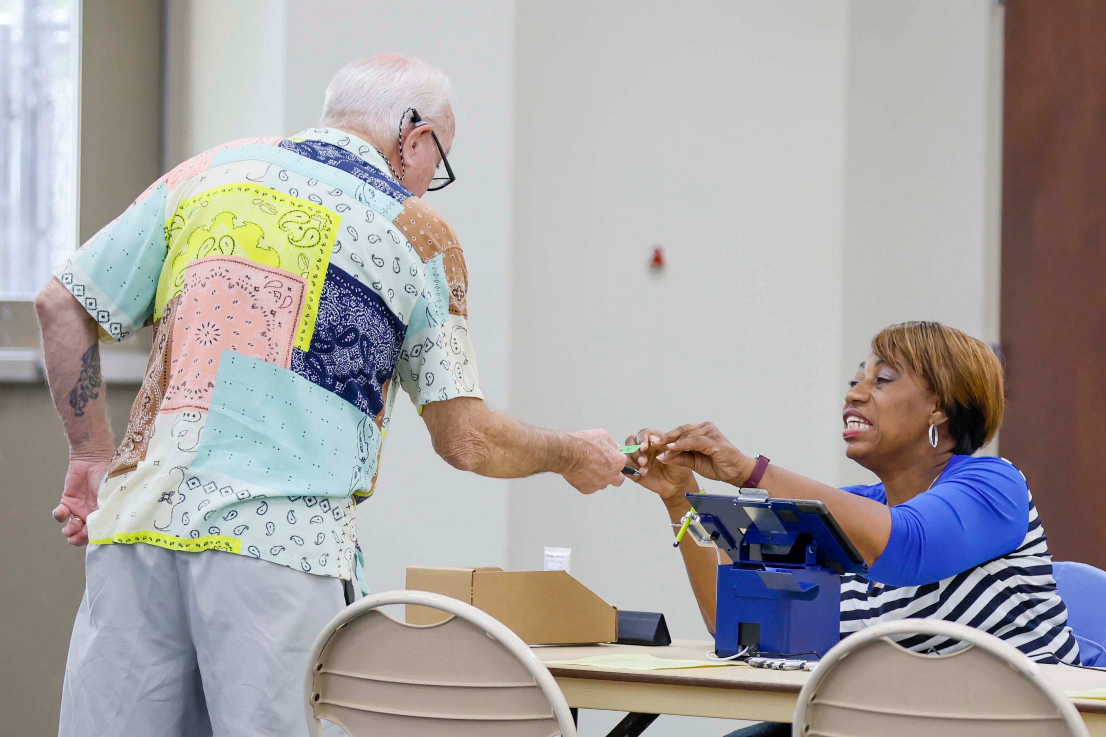 Nathan Harvey gets his voting card from a poll worker at Calvary Baptist Church in Austell during the Georgia Public Service Commission’s special election in June. (Miguel Martinez/AJC)