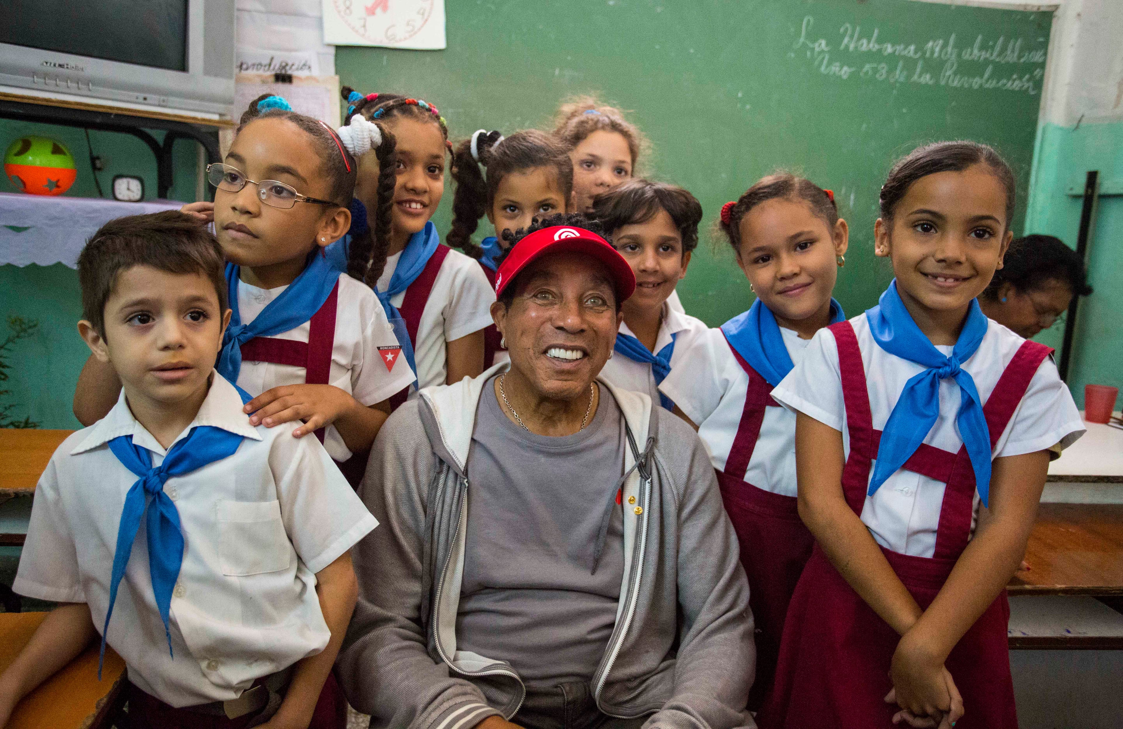 American artist Smokey Robinson poses for a picture with students of the Miguel Fernandez Roig primary school in Havana, Cuba, Tuesday, April 19, 2016. The U.S. President's Committee on Arts and the Humanities, including musicians Smokey Robinson, Usher and Dave Matthews, are on a four-day visit in Cuba. (AP Photo/Desmond Boylan)